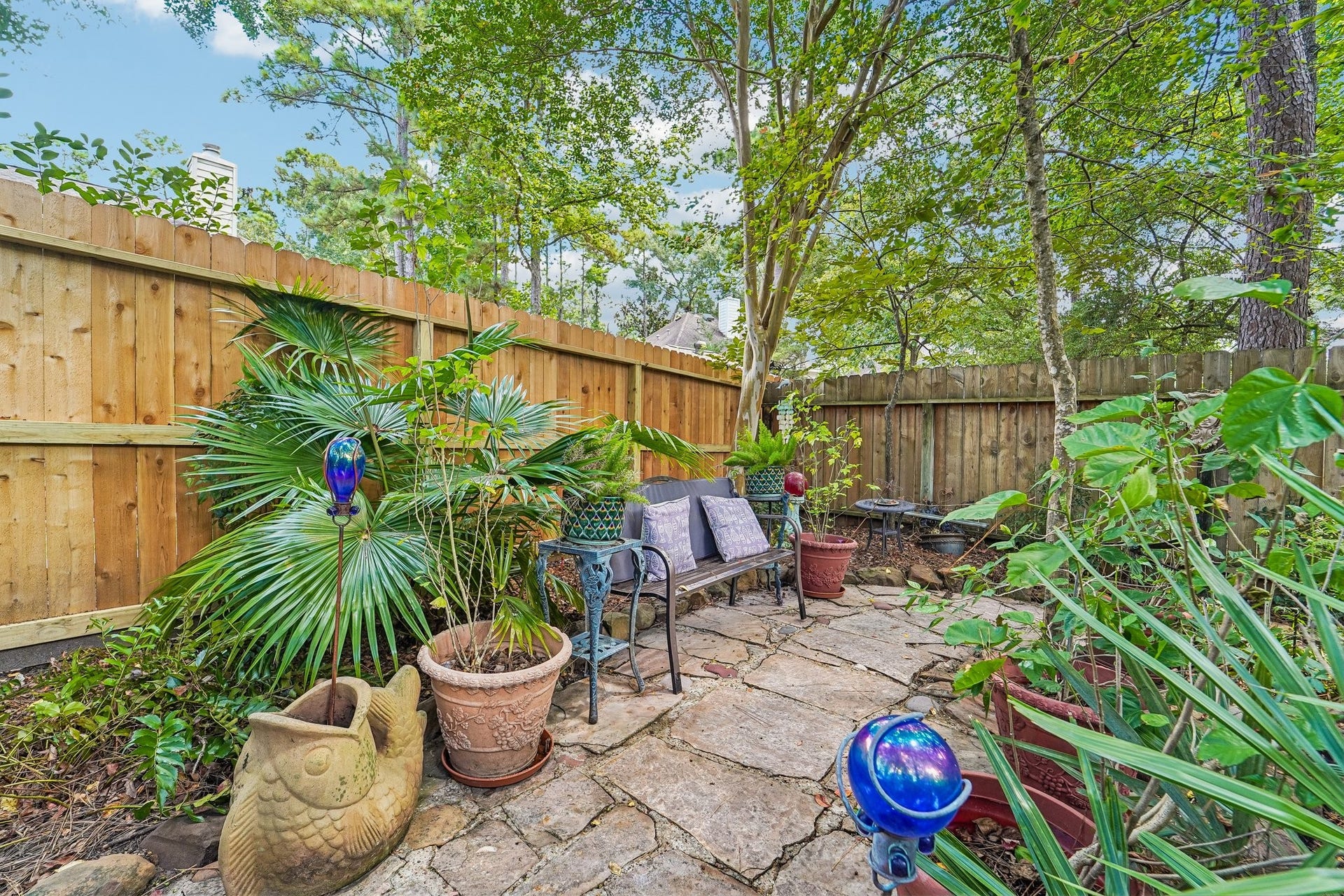 14 Serene Creek Place, The Woodlands, TX 77382 Charming garden retreat featuring a cozy seating area surrounded by lush greenery and colorful accents, perfect for relaxation and outdoor enjoyment.