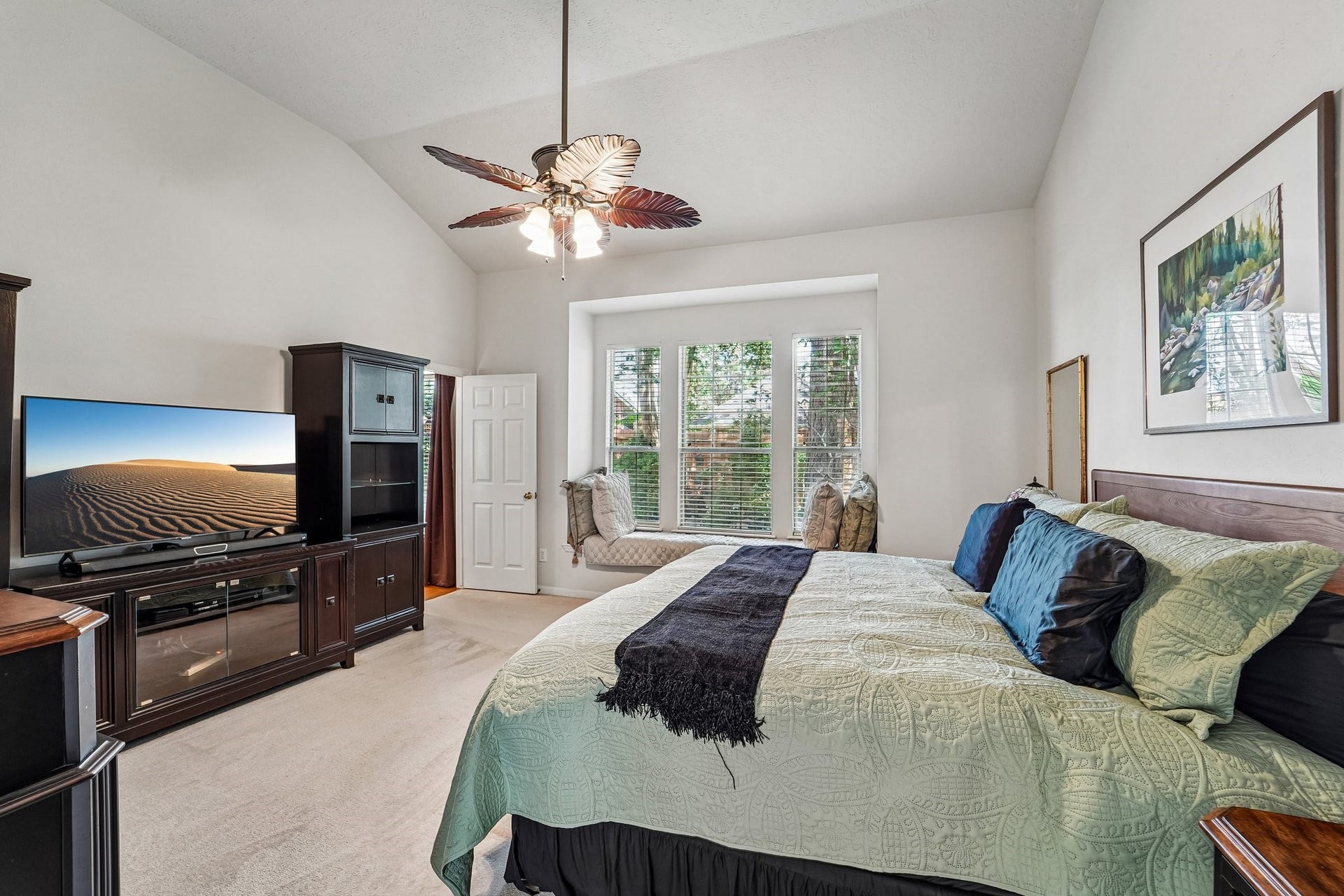 14 Serene Creek Place, The Woodlands, TX 77382 Spacious primary bedroom featuring a vaulted ceiling, elegant ceiling fan, and ample natural light.
