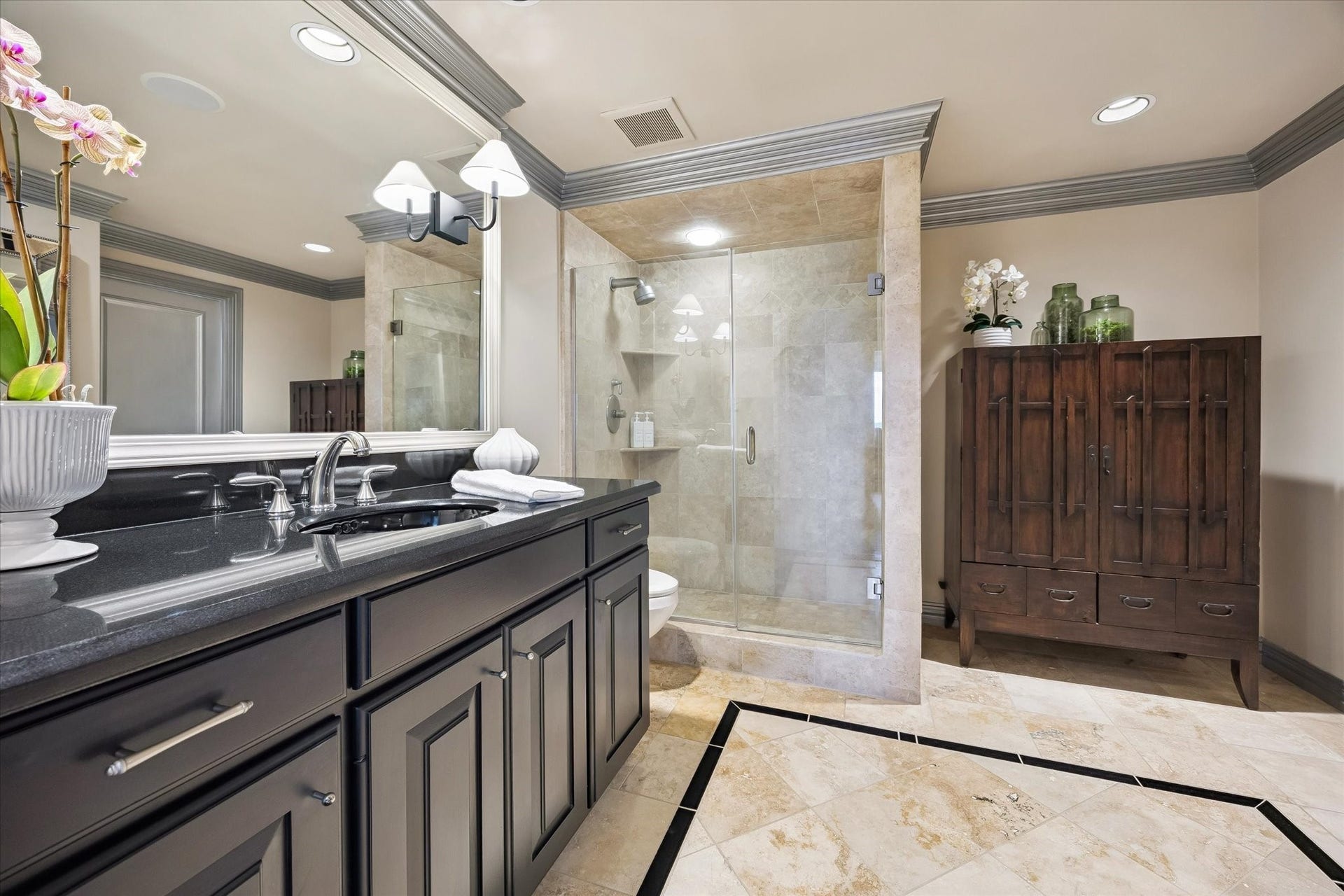 49 Briar Hollow Lane, #702, Houston, TX 77027 Secondary bath with oversized, walk-in shower with frameless glass doors, extended vanity and travertine accents.