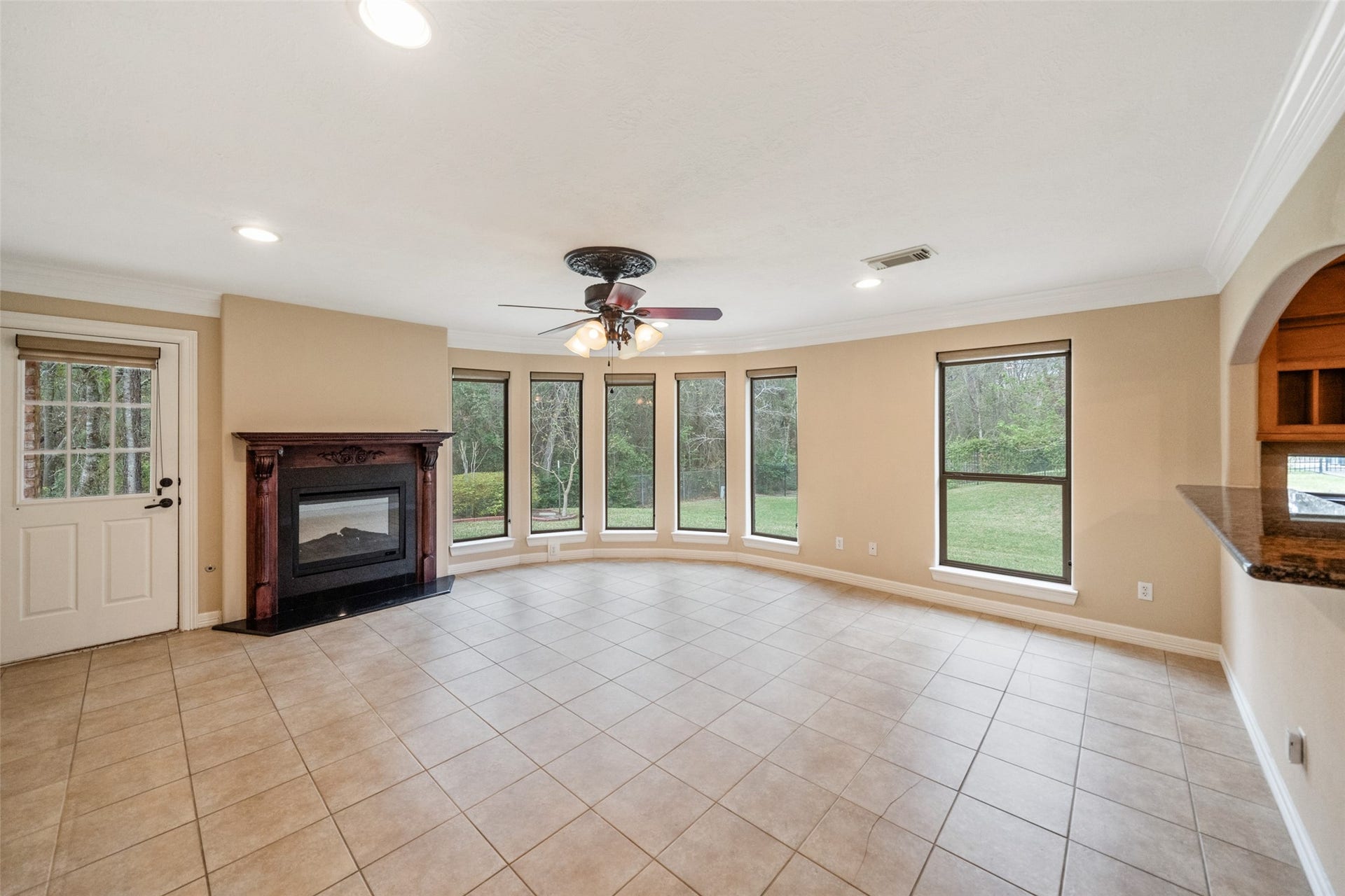 901 Longmire Road, #28, Conroe, TX 77304 This spacious living room features a cozy fireplace, large windows offering plenty of natural light, tiled floors, and a ceiling fan. Its open design provides a welcoming and airy feel, perfect for relaxation or entertaining.