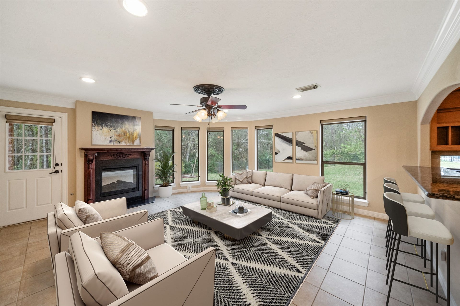 901 Longmire Road, #28, Conroe, TX 77304 Spacious living room with large windows offering plenty of natural light. Features a cozy fireplace, modern ceiling fan, and elegant tile flooring. Virtually Staged living area adjacent to breakfast bar with stools.