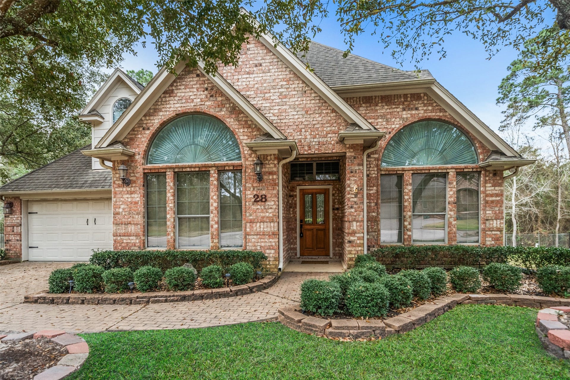 901 Longmire Road, #28, Conroe, TX 77304 Charming brick home features a classic design with large arched windows and a welcoming wooden front door.
