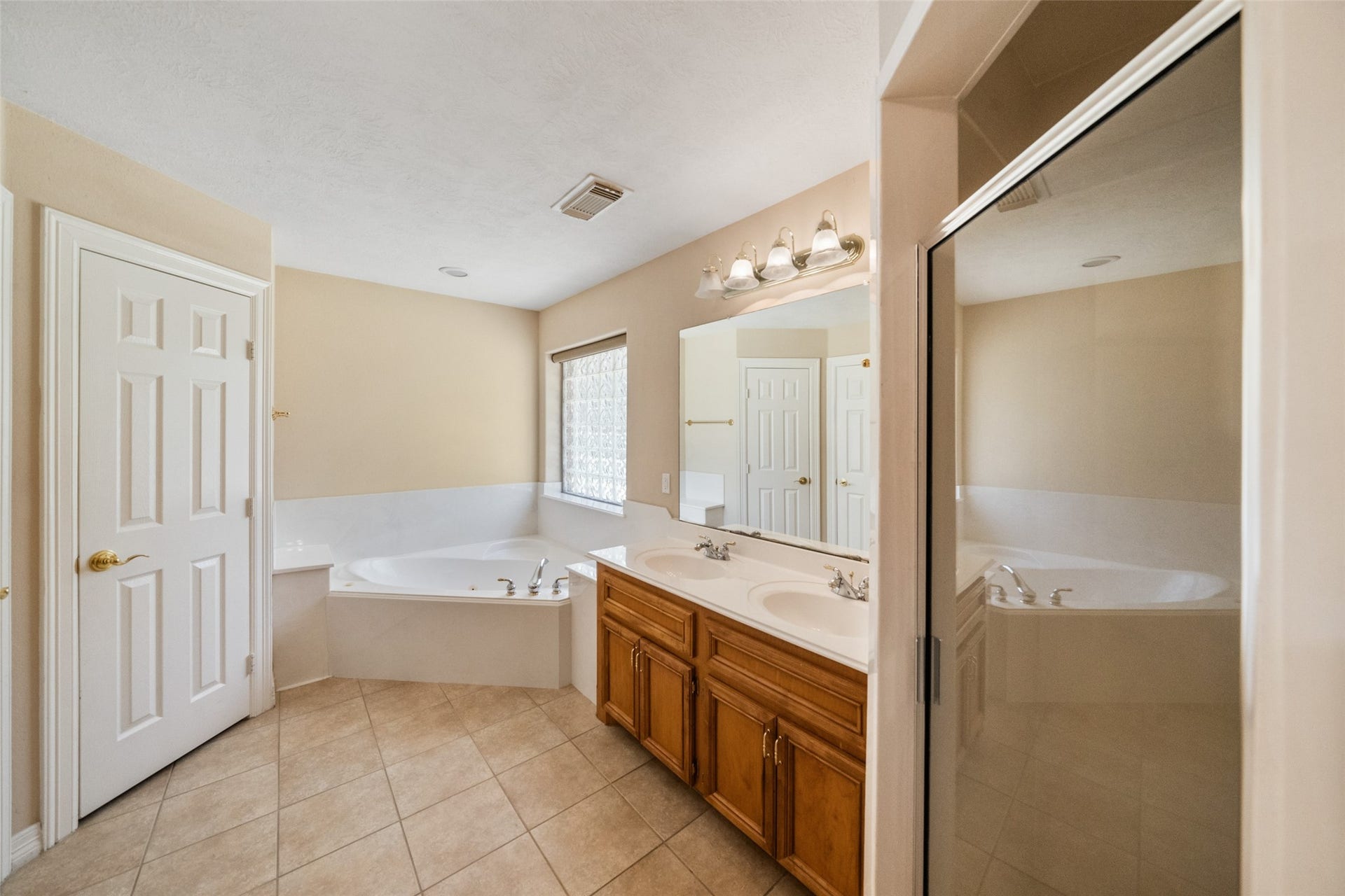 901 Longmire Road, #28, Conroe, TX 77304 Primary bathroom features a spacious layout with a corner bathtub, dual sinks with wooden cabinets, a large mirror, private toilet, linen closet, spacious walk in closet and a separate enclosed shower.