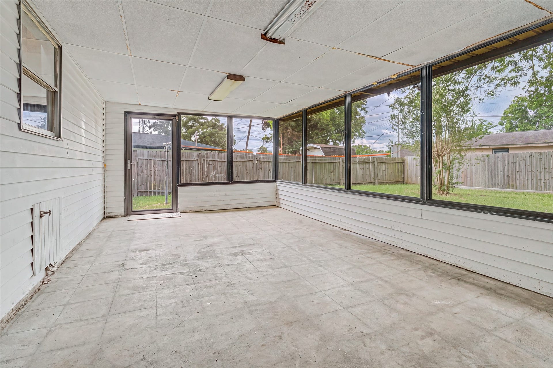Spacious sunroom with large windows offers a bright, versatile area overlooking the backyard, perfect for relaxation or entertaining.