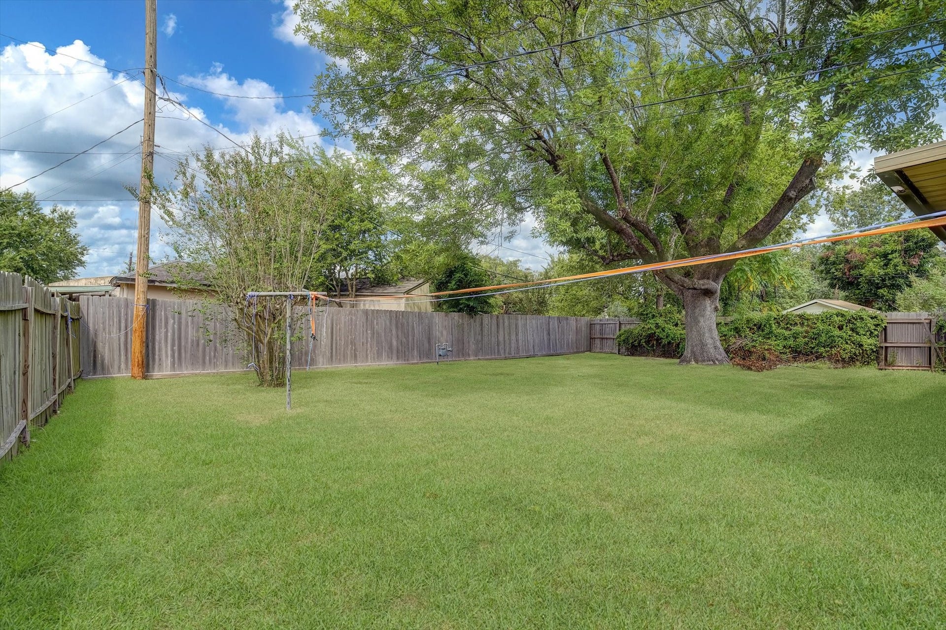 Home with a spacious backyard, mature tree, and covered patio perfect for outdoor relaxation and entertaining.