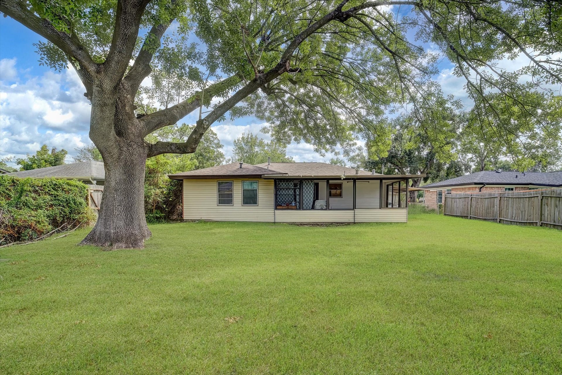 Spacious backyard, mature tree, and covered patio perfect for outdoor relaxation and entertaining.