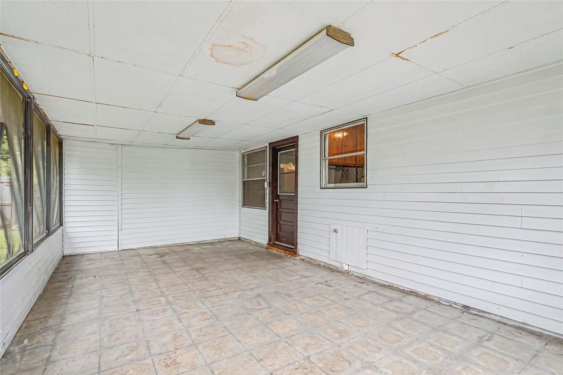 Spacious enclosed porch with tile flooring and ample natural light, perfect for relaxing or entertaining.