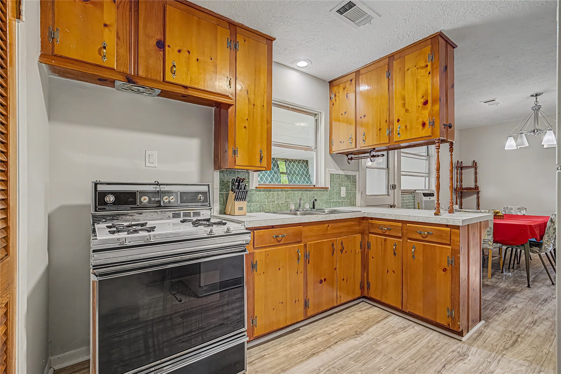 Charming kitchen with wood cabinetry, a classic gas stove, and a cozy breakfast bar overlooking the dining area.