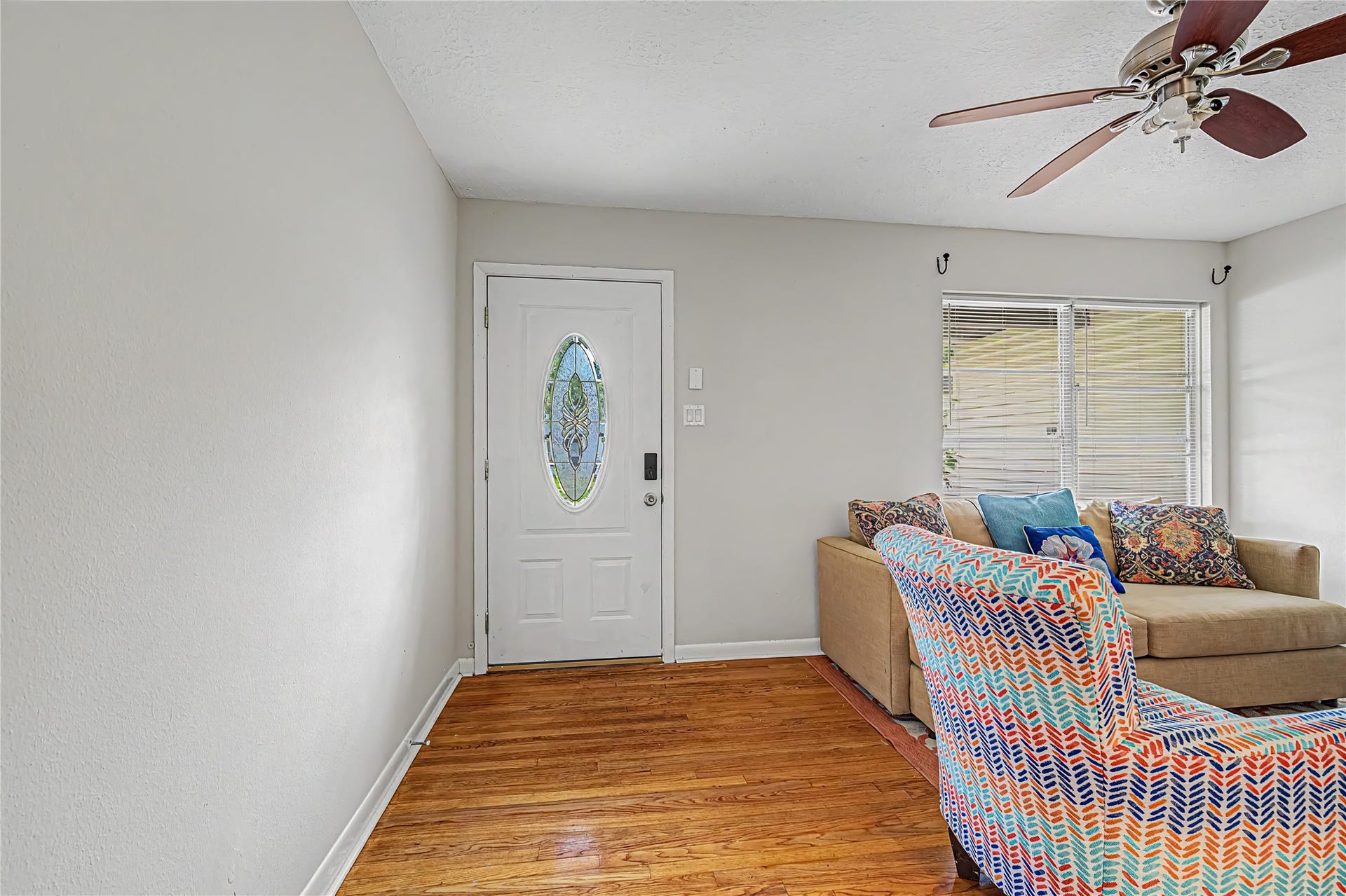Inviting living space with warm hardwood floors. A decorative front door adds charm and natural light streams through the window, creating a bright and airy atmosphere.