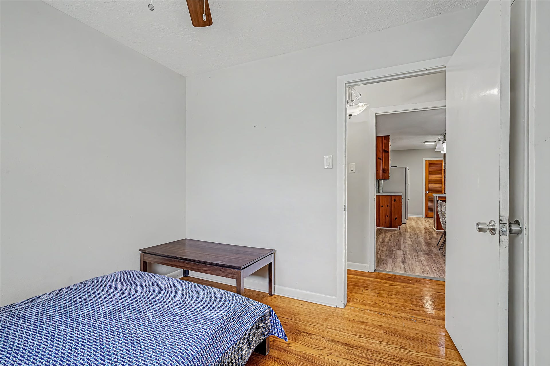 Cozy bedroom with hardwood floors, offering a simple layout and direct access to the hall way.