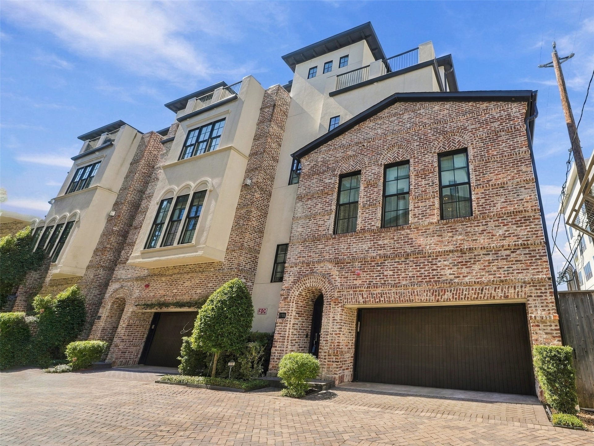 1306 Castle Court, Houston, TX 77006 Four-story brick-and-stucco exterior with an attached garage tucked off the private drive.