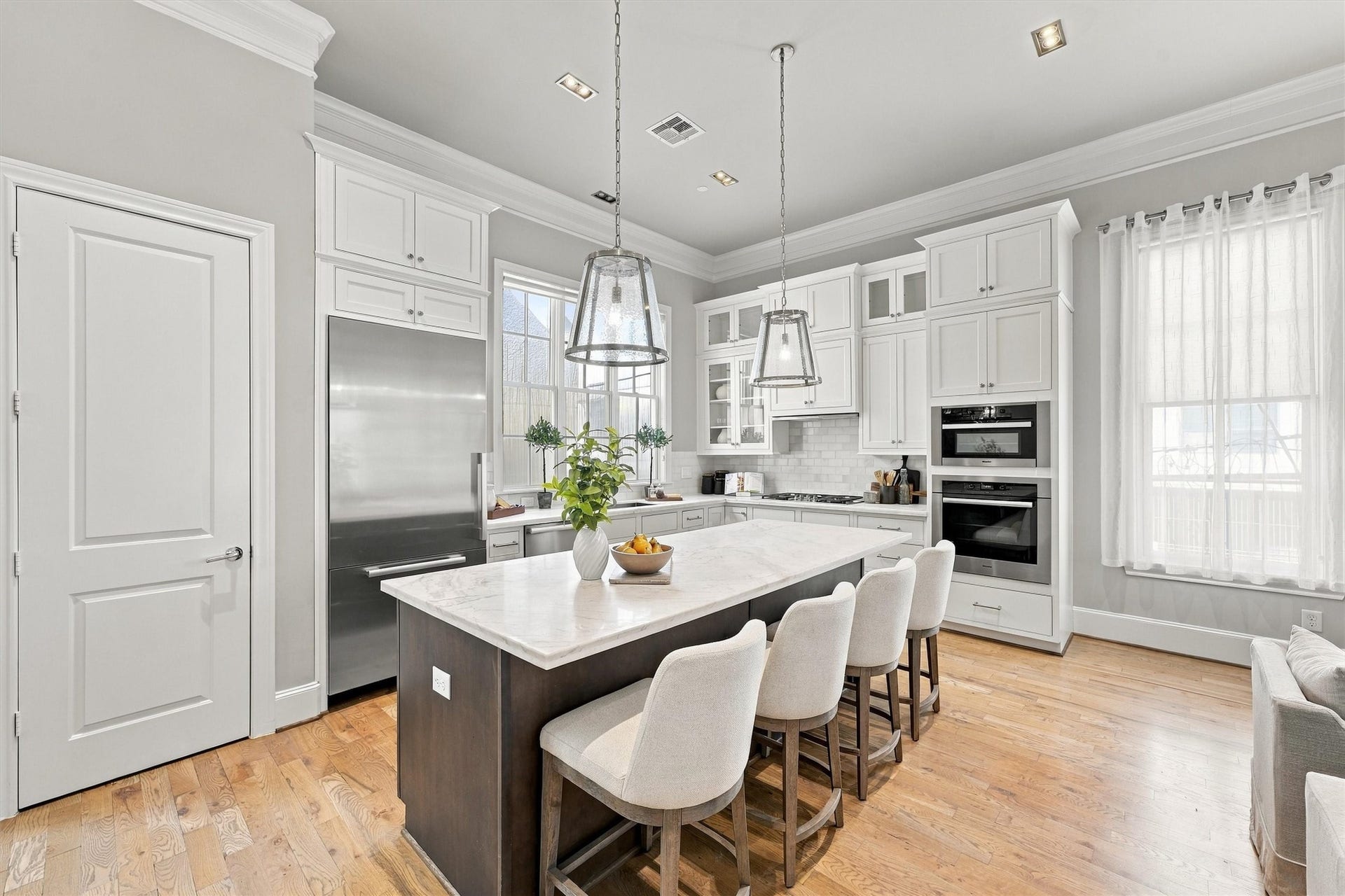 1306 Castle Court, Houston, TX 77006 Kitchen with white shaker cabinetry to the crown, glass-front uppers and seating for four at the island