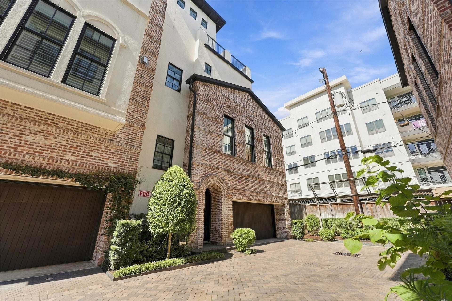 1306 Castle Court, Houston, TX 77006 Four-story brick-and-stucco exterior with an attached garage tucked off the private drive.
