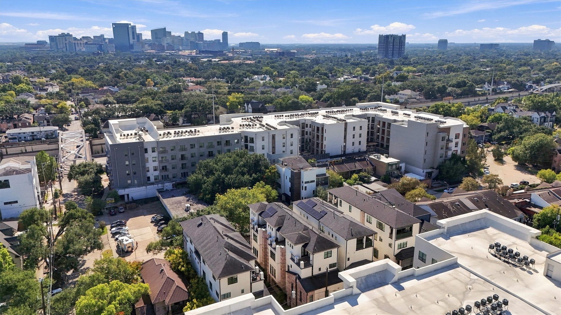 1306 Castle Court, Houston, TX 77006 Montrose rooftops beneath a mature tree canopy, with the city skyline beyond