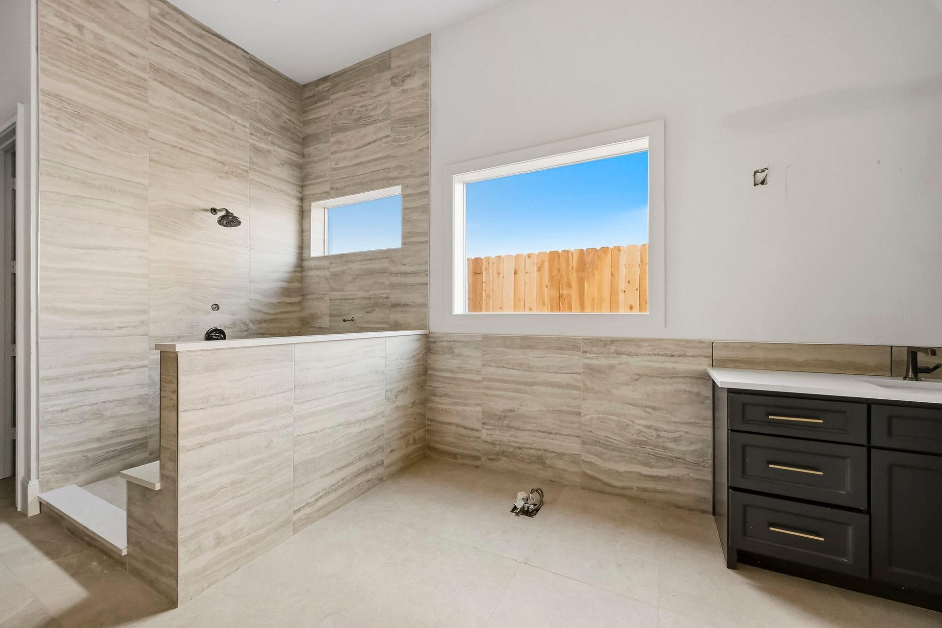 6618 Sivley Street, Hockley, TX 77055 Luxurious walk-in shower with elegant tile work, a large window for natural light, and a sleek dark vanity!
