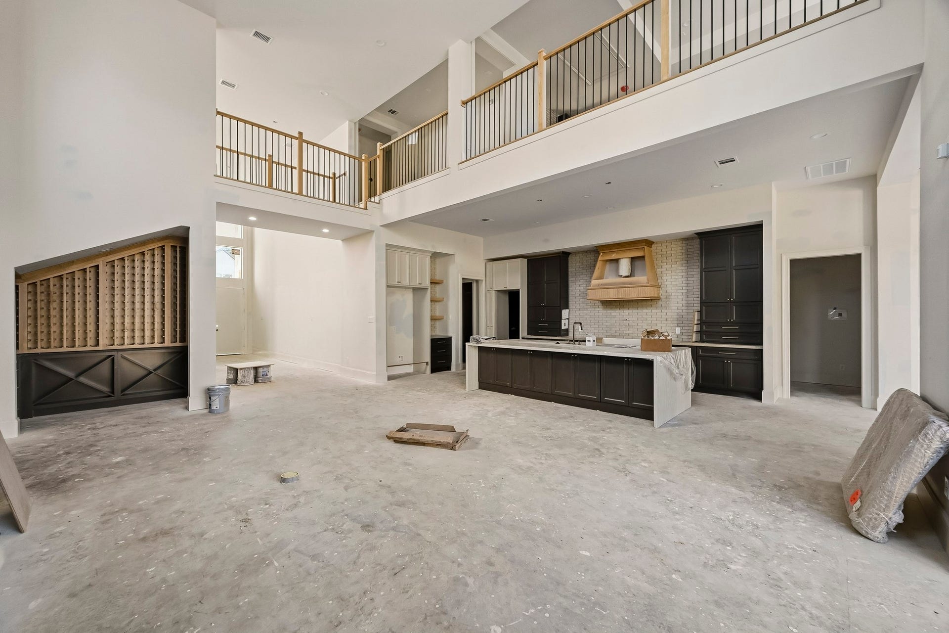 6618 Sivley Street, Hockley, TX 77055 Spacious open-concept living area with high ceilings, a modern kitchen featuring dark cabinetry and a central island, and a second-story overlook with elegant railing details!