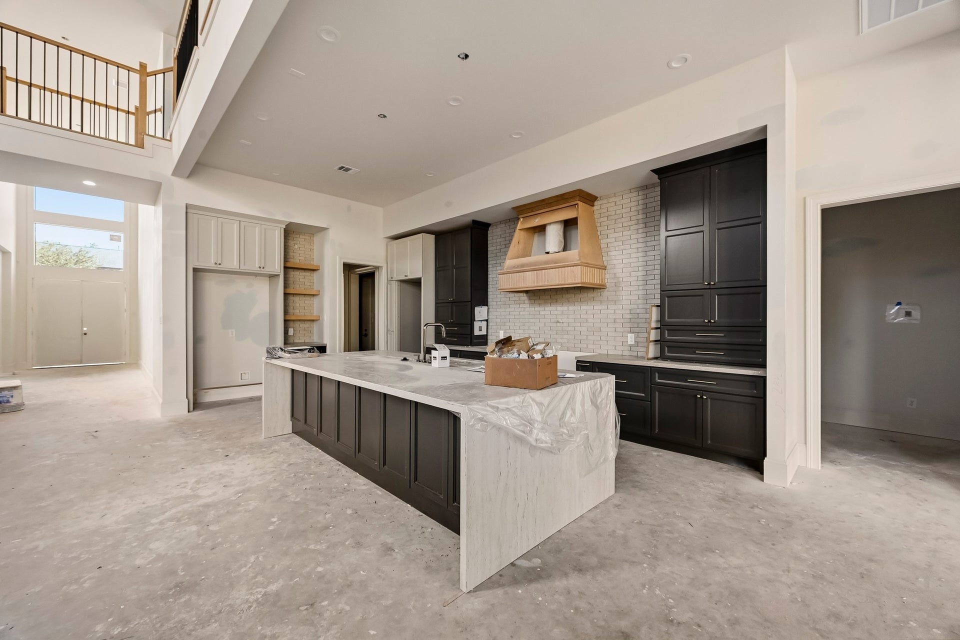 6618 Sivley Street, Hockley, TX 77055 Spacious modern kitchen featuring elegant dark cabinetry, a large island with marble countertop, and high ceilings for an airy feel!