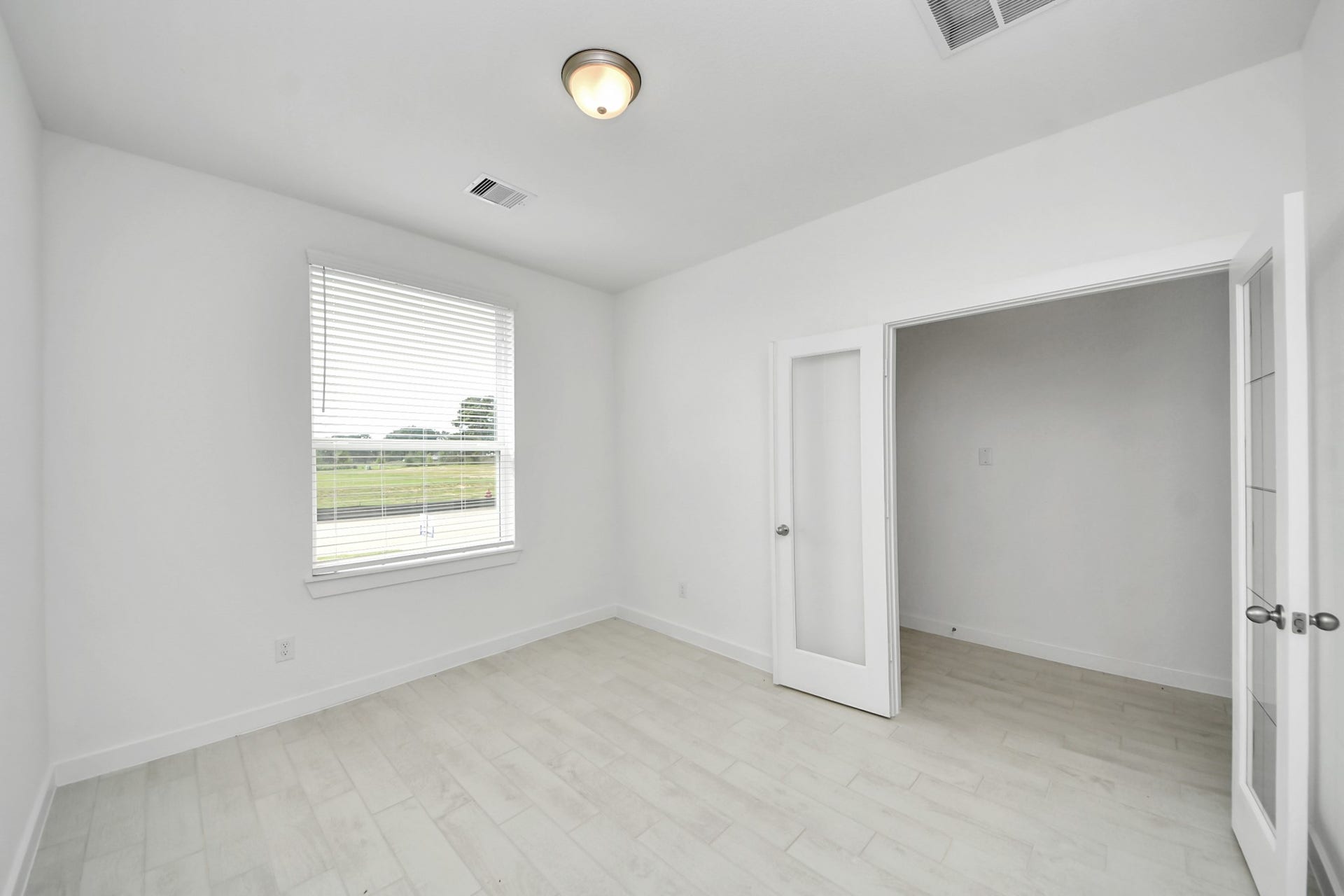 Experience the perfect blend of sophistication and warmth in this home office, boasting elegant wood-look tile flooring and flooded with natural light from expansive windows and French doors. Sample photo of completed home with similar floor plan. Actual colors and selections may vary.