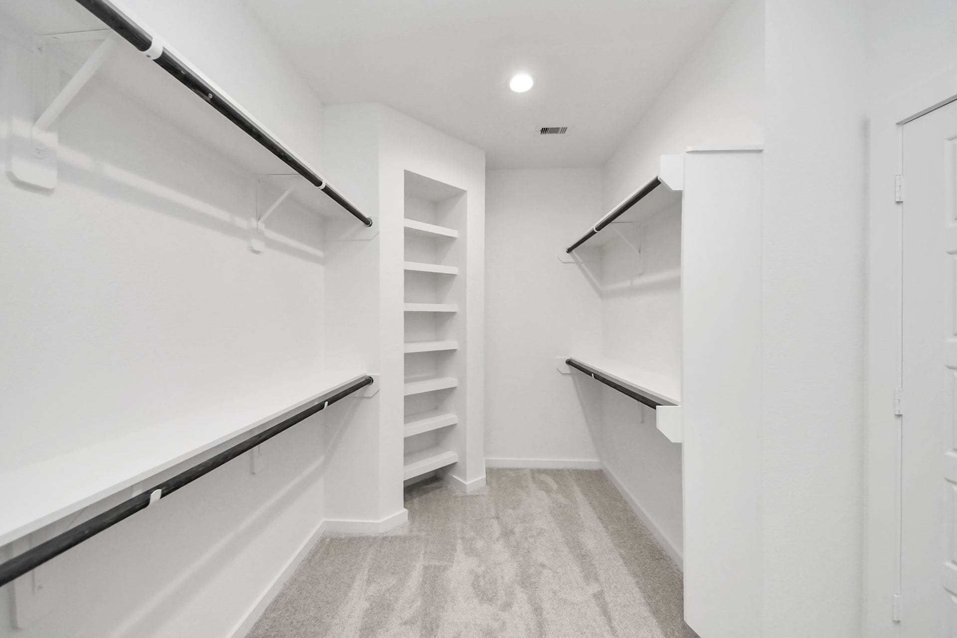 Walk-in closet that epitomizes luxury and practicality. This generously sized space features built-in shelving, offering abundant room for impeccable organization. High ceilings and recessed lighting create a bright and welcoming ambiance. Sample photo of completed home with similar floor plan. Actual colors and selections may vary.