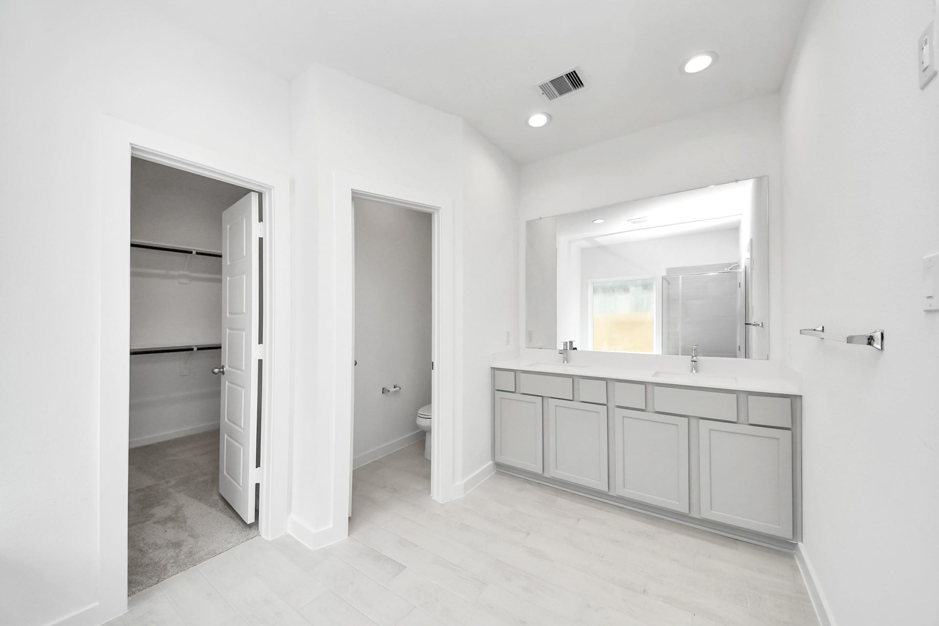 Elevate your daily routine at the elegant vanity, now equipped with double sinks, light countertops, modern hardware, and beautiful recessed lights. Sample photo of completed home with similar floor plan. Actual colors and selections may vary.