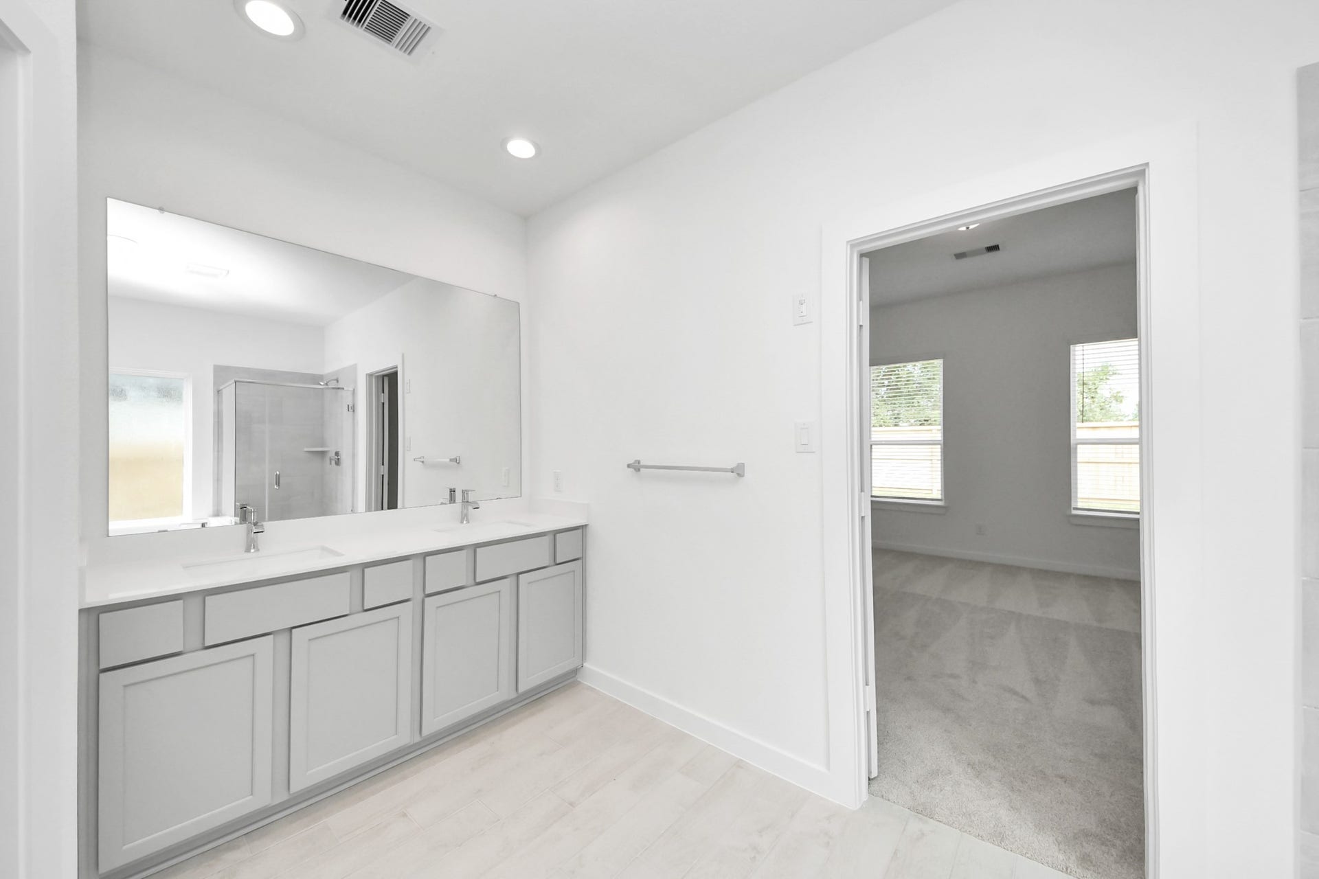 Elevate your daily routine at the elegant vanity, now equipped with double sinks, light countertops, modern hardware, and beautiful recessed lights. Sample photo of completed home with similar floor plan. Actual colors and selections may vary.