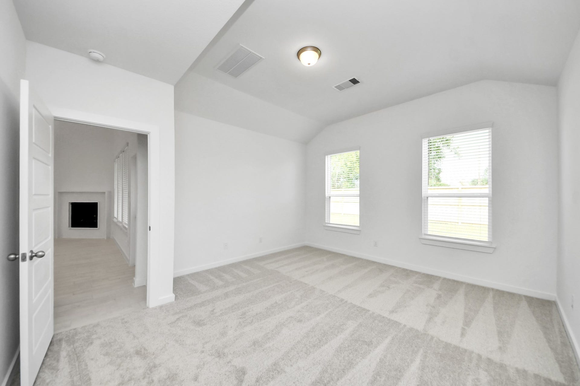 Escape and relax in the exquisite primary suite, a haven to unwind after a long day. The spacious room, located on first floor, boasts plush carpeting, soothing paint tones, high ceilings, and expansive windows adorned with privacy blinds. Sample photo of completed home with similar floor plan. Actual colors and selections may vary.