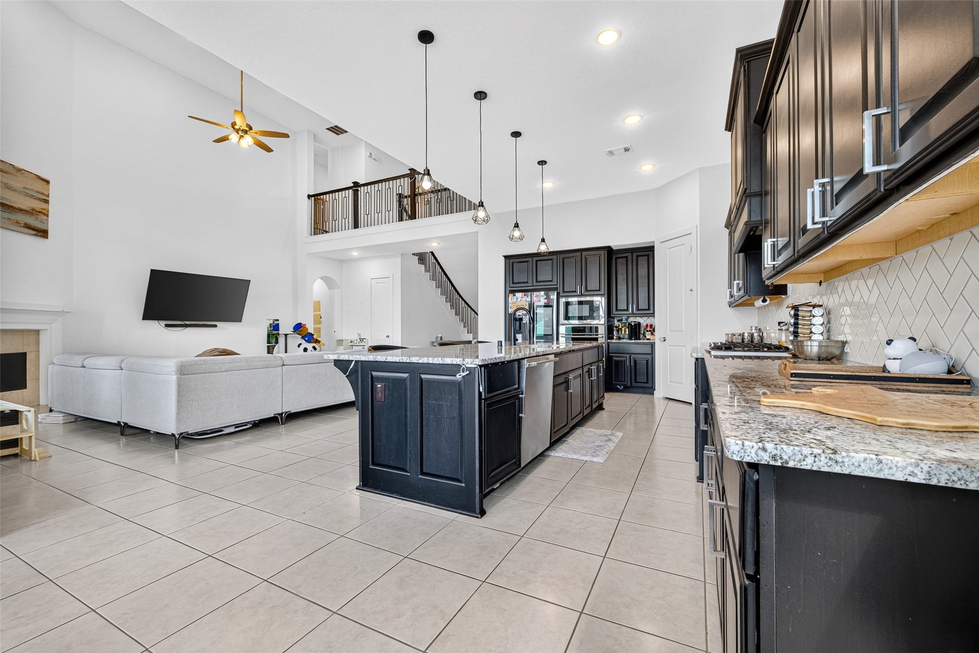 10114 Brush Way, Rosharon, TX 77583 Spacious open-concept living area with high ceilings, elegant dark cabinetry, and a large kitchen island, perfect for entertaining and family gatherings.