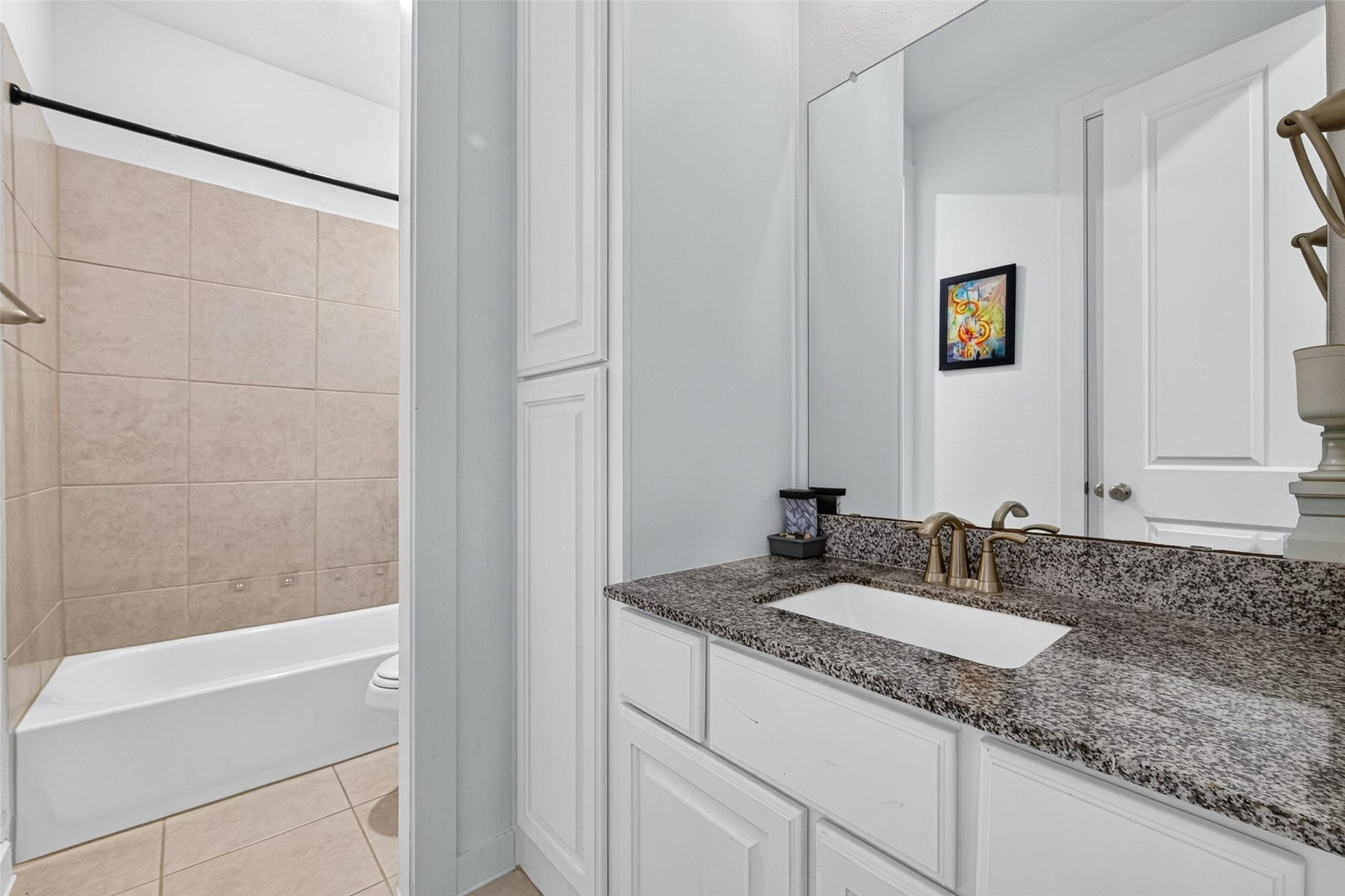 10114 Brush Way, Rosharon, TX 77583 Elegant bathroom featuring a granite countertop, sleek white cabinetry, and a tiled shower-tub combination for a modern touch.