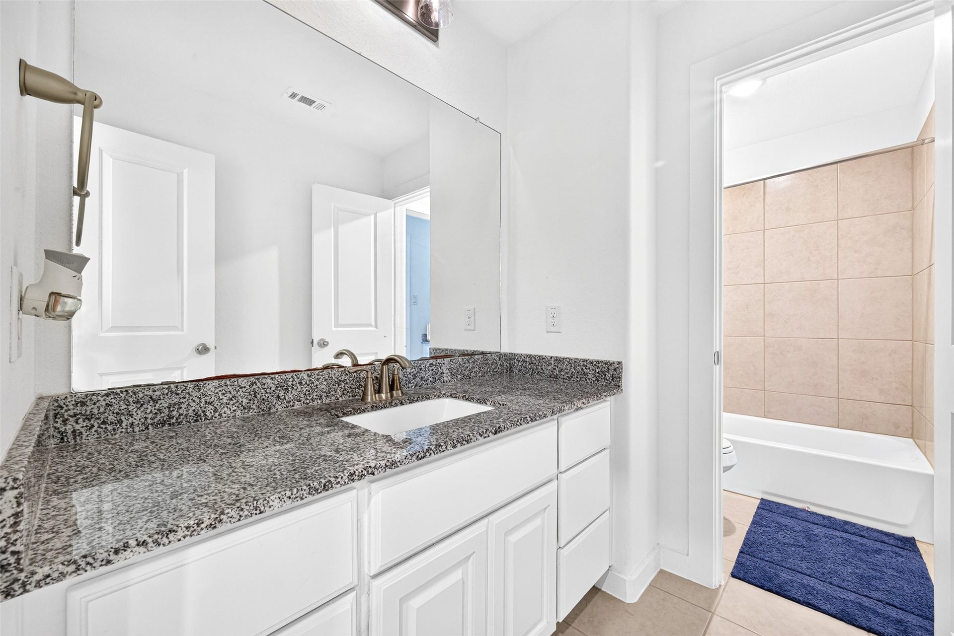 10114 Brush Way, Rosharon, TX 77583 Bright and modern bathroom featuring a sleek granite countertop, ample storage with white cabinetry, and a tiled shower area for a clean, contemporary feel.
