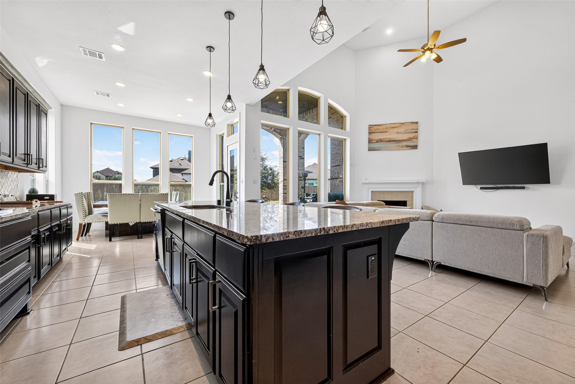10114 Brush Way, Rosharon, TX 77583 A spacious open-concept living area features a sleek kitchen with dark cabinetry and a large island, flowing seamlessly into a bright dining space and cozy living room with high ceilings and abundant natural light.