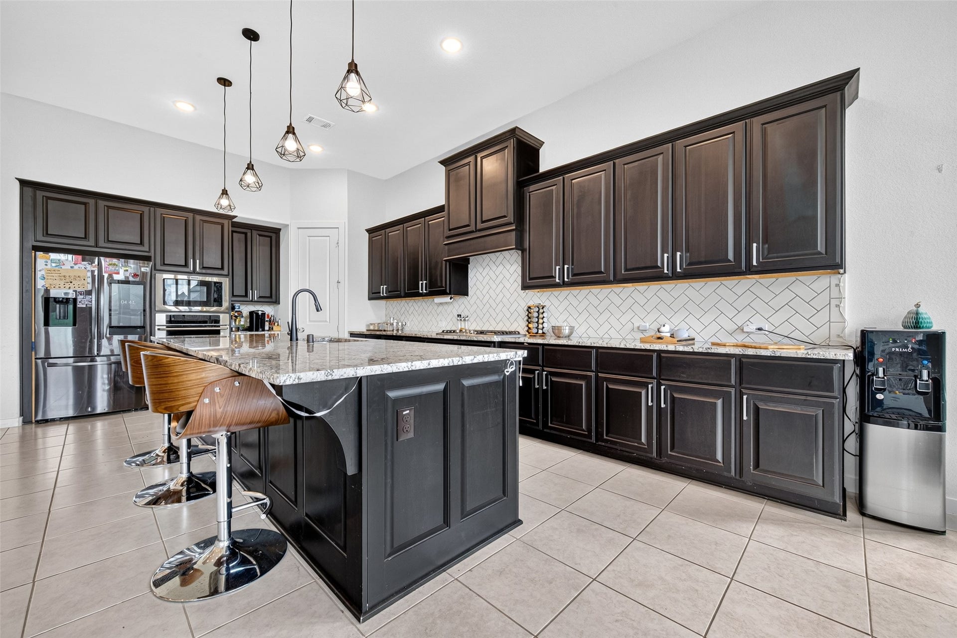 10114 Brush Way, Rosharon, TX 77583 Spacious kitchen with elegant dark wood cabinetry, sleek granite countertops, and a modern island with stylish pendant lighting, perfect for entertaining.