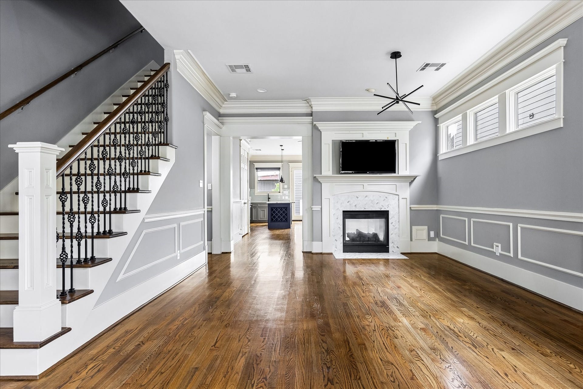 1332 W 21st Street, #B, Houston, TX 77008 An elegant staircase with ornamental iron balusters, rich hardwood floors, and a beautifully framed fireplace lend timeless character to the living room.