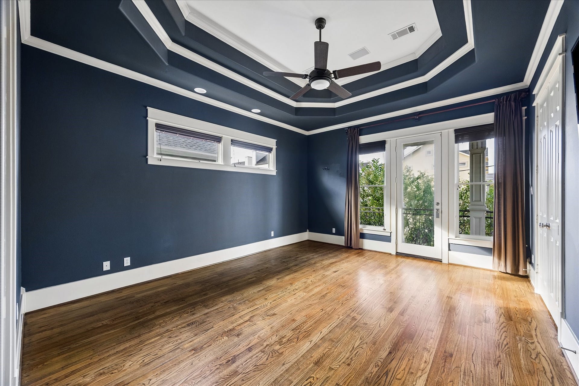 1332 W 21st Street, #B, Houston, TX 77008 A striking double-tiered tray ceiling, rich navy walls, and contrasting white trim lend distinctive character to the spacious primary suite.