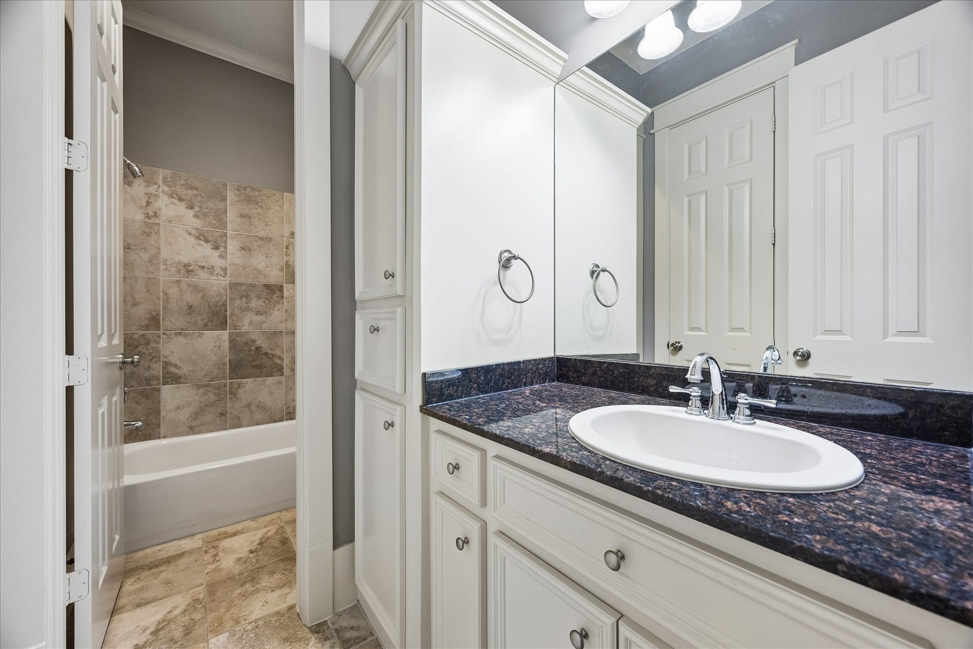1332 W 21st Street, #B, Houston, TX 77008 The shared Jack-and-Jill bath features a granite-topped vanity, generous cabinetry, and a tub-shower combination.