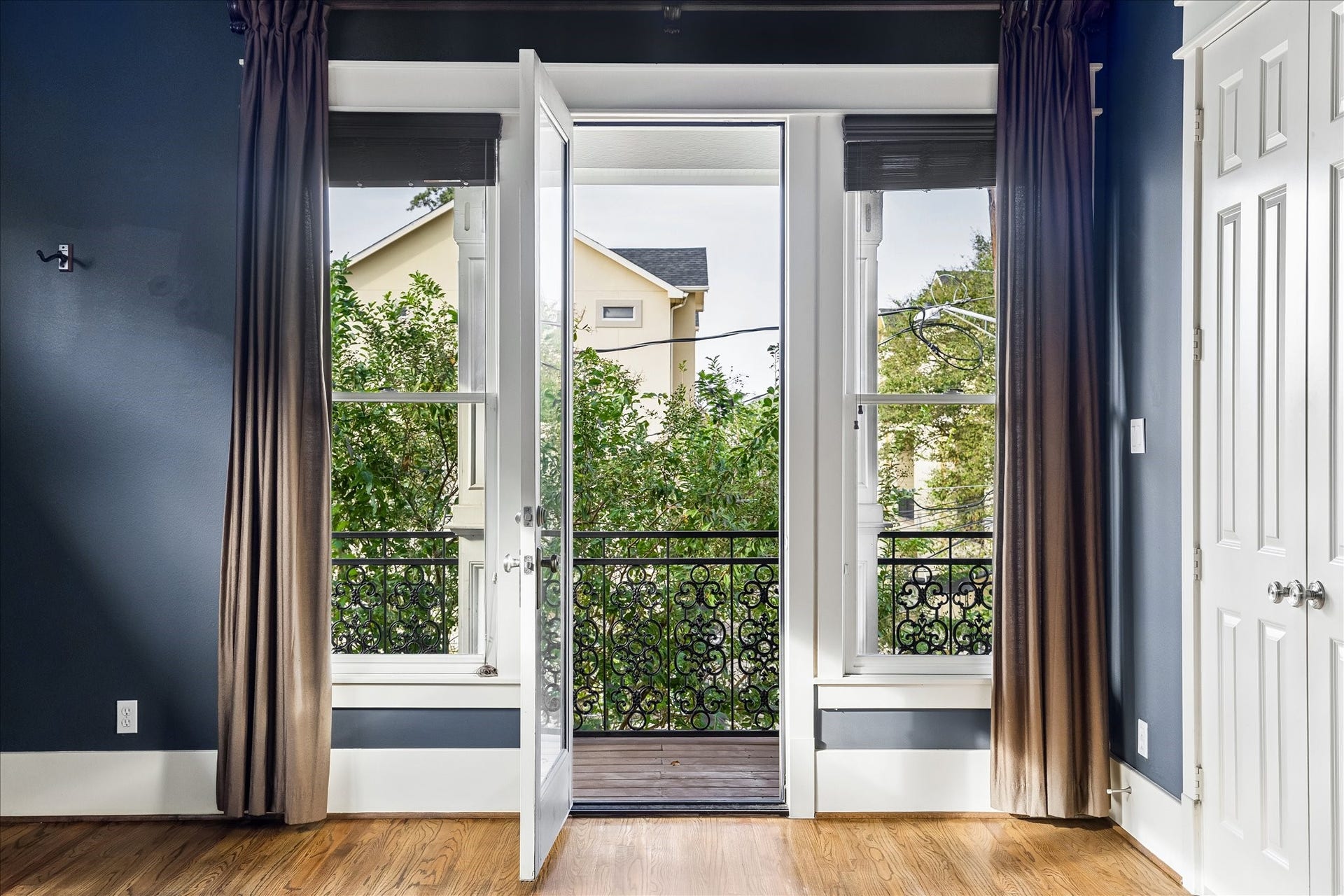1332 W 21st Street, #B, Houston, TX 77008 A glass door flanked by tall windows opens to the private covered balcony, bringing natural light and leafy views into the primary suite.