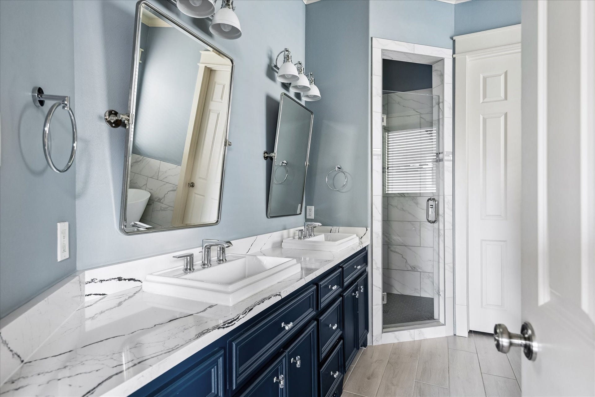 1332 W 21st Street, #B, Houston, TX 77008 Polished fixtures, individual vanity mirrors, and a glass-enclosed shower complement the bathroom's refined finishes.