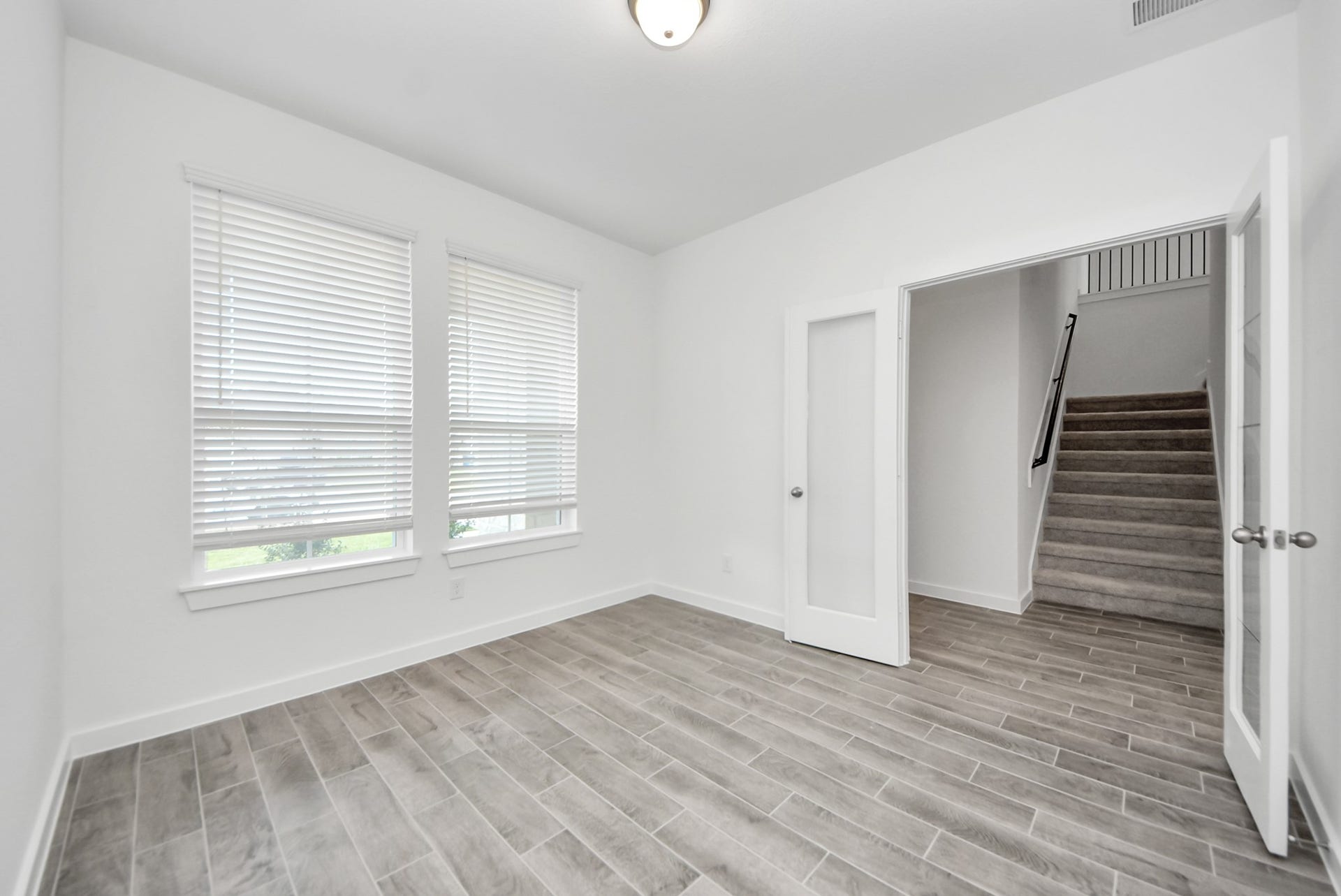 11119 Rose River Drive, Houston, TX 77044 Experience the perfect blend of sophistication and warmth in this home office, boasting elegant wood-look tile flooring and flooded with natural light from expansive windows and French doors.