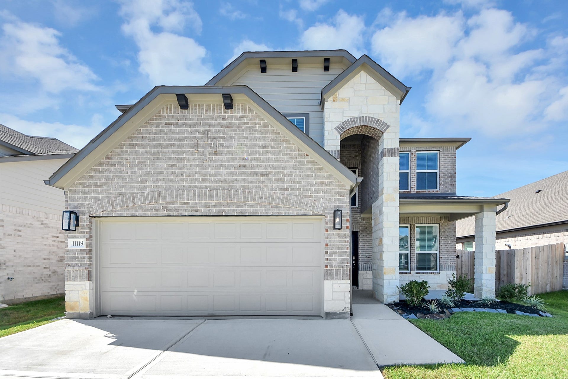 11119 Rose River Drive, Houston, TX 77044 This home boasts lush green grass and meticulous landscaping. Its premium elevation showcases an exquisite blend of brick and stone features, complemented by modern coach lighting