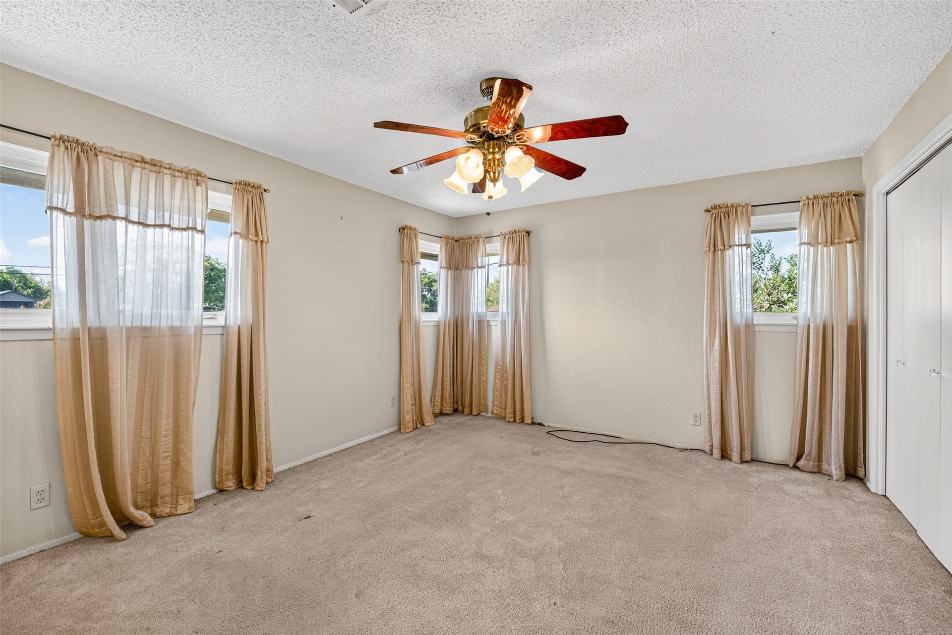 Primary bedroom facing the front of the house with multiple closets and ceiling fan