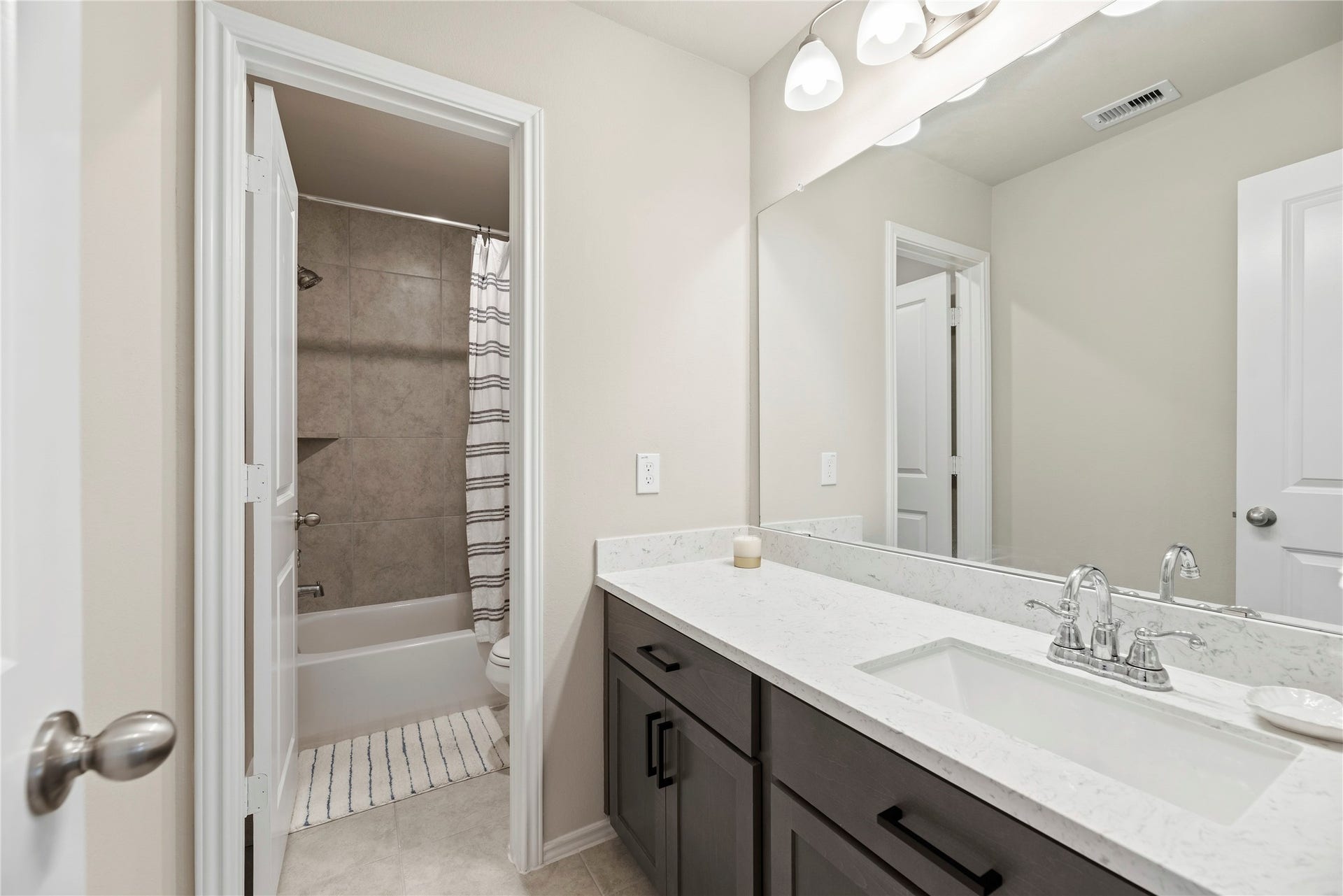 12914 Catfish River Court, Cypress, TX 77433 This third bathroom, located upstairs, features a modern vanity with extra storage. It includes a shower-tub combo with an additional privacy door.