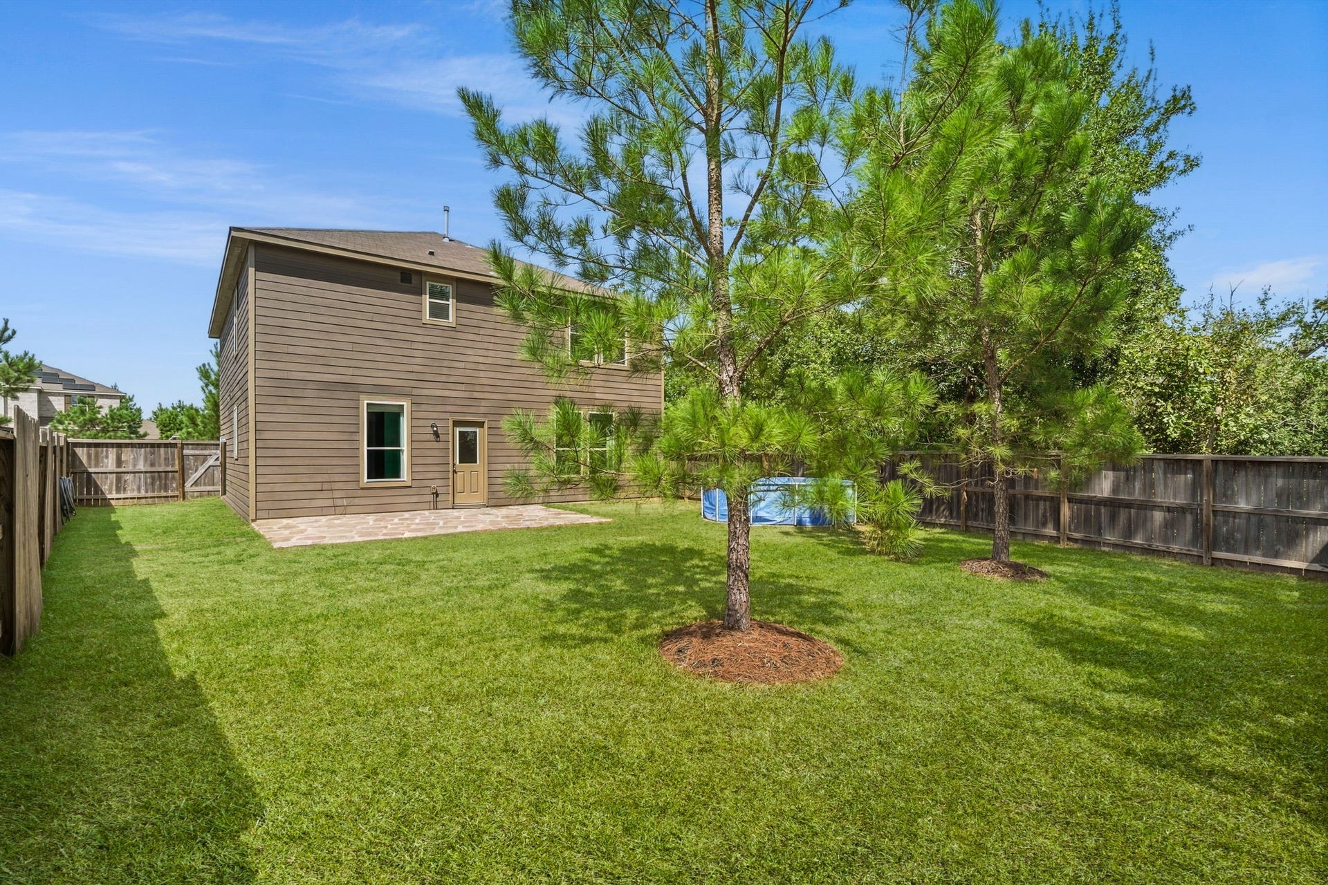 122 Ashwood Glade Lane, Conroe, TX 77378 Spacious backyard with lush green lawn, mature trees, and a privacy fence, perfect for outdoor activities and relaxation.