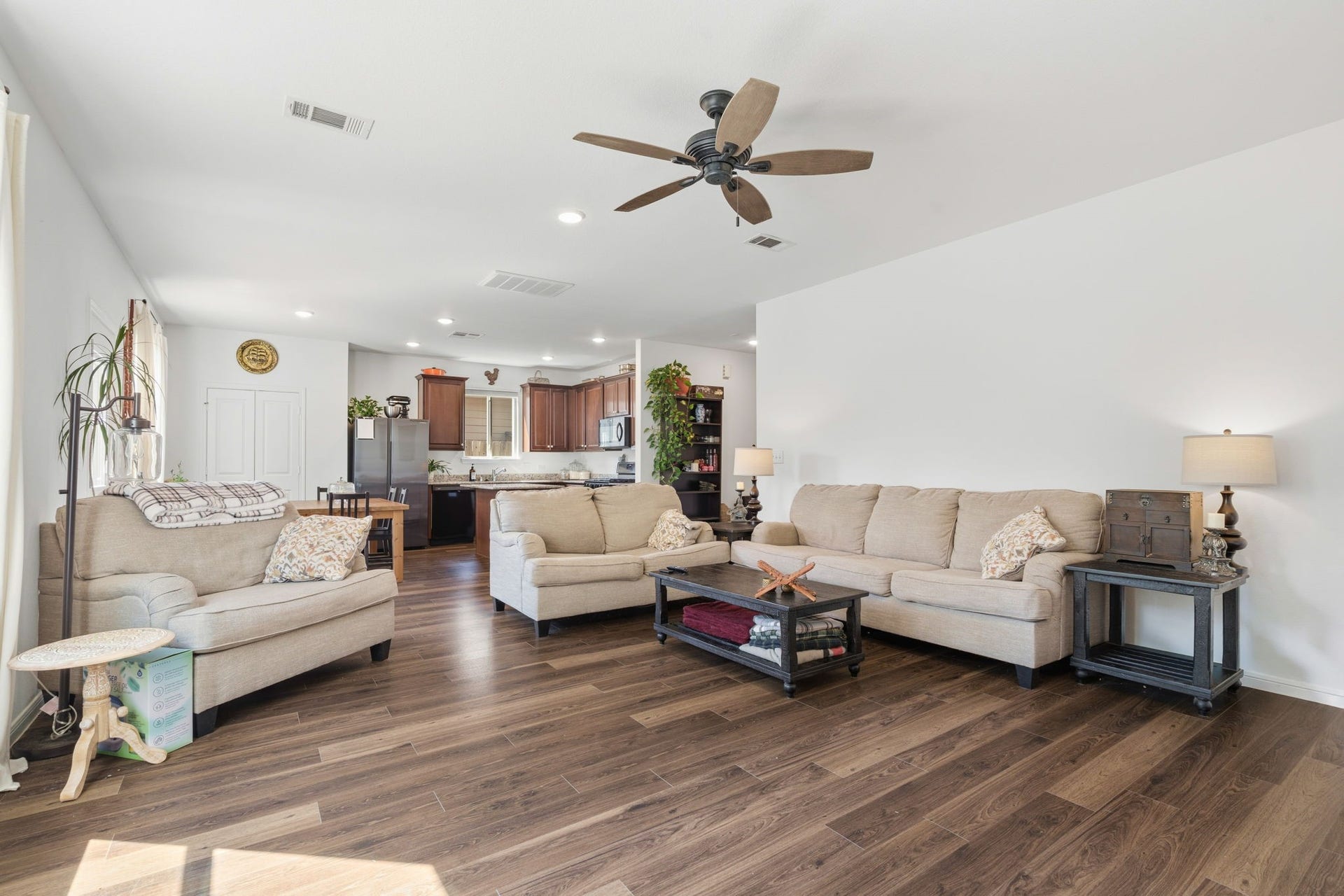 122 Ashwood Glade Lane, Conroe, TX 77378 Spacious open-concept living area with elegant hardwood flooring, cozy seating, and a ceiling fan, seamlessly connecting to a modern kitchen with rich cabinetry.