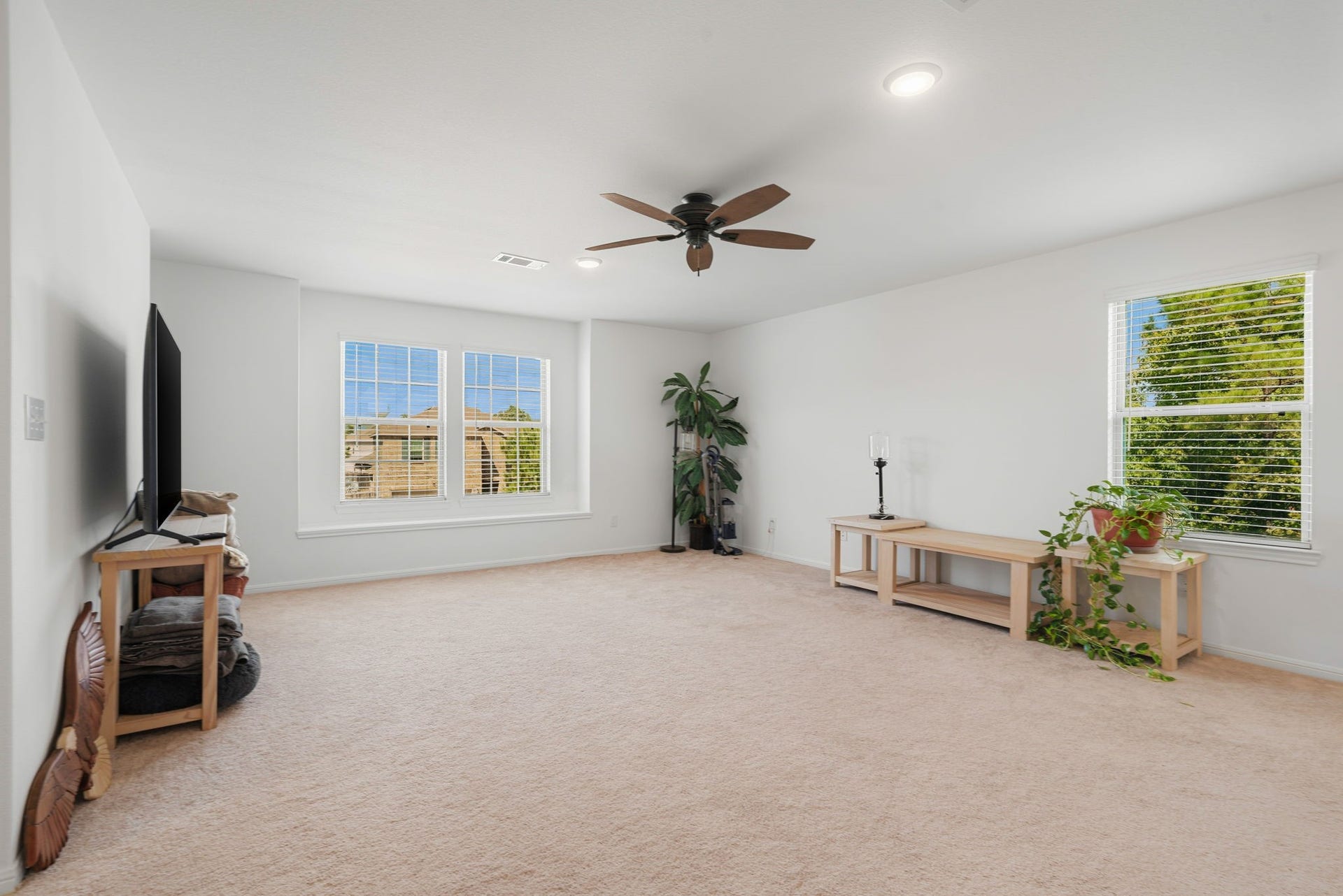 122 Ashwood Glade Lane, Conroe, TX 77378 Spacious and bright living area featuring large windows, neutral carpeting, and a ceiling fan, perfect for relaxation and entertaining.