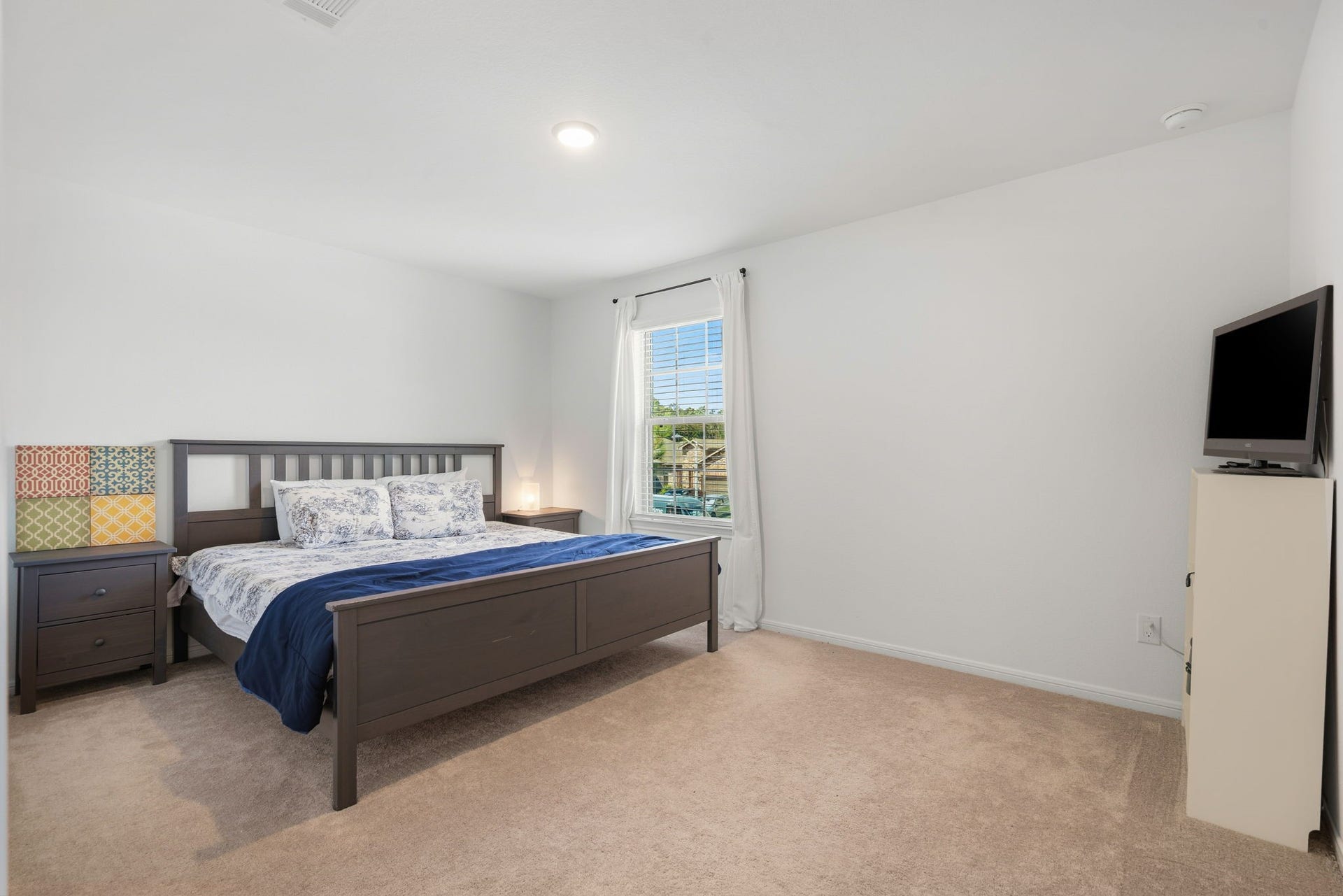 122 Ashwood Glade Lane, Conroe, TX 77378 Spacious bedroom with natural light, featuring a cozy bed, a bedside table, and a TV, perfect for relaxation.