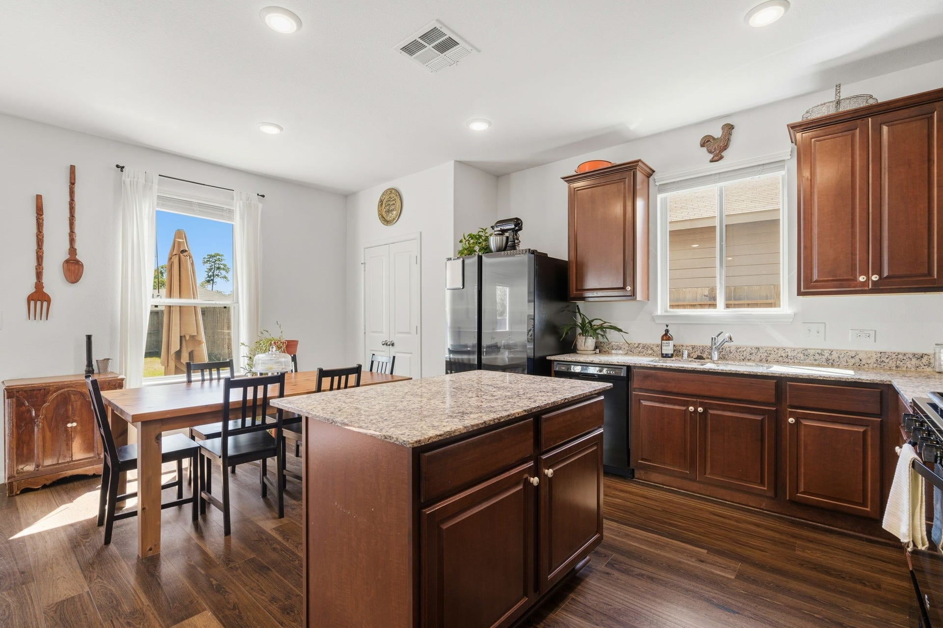 122 Ashwood Glade Lane, Conroe, TX 77378 Bright and inviting kitchen featuring rich wooden cabinetry, granite countertops, and an island, seamlessly connected to a cozy dining area with ample natural light.