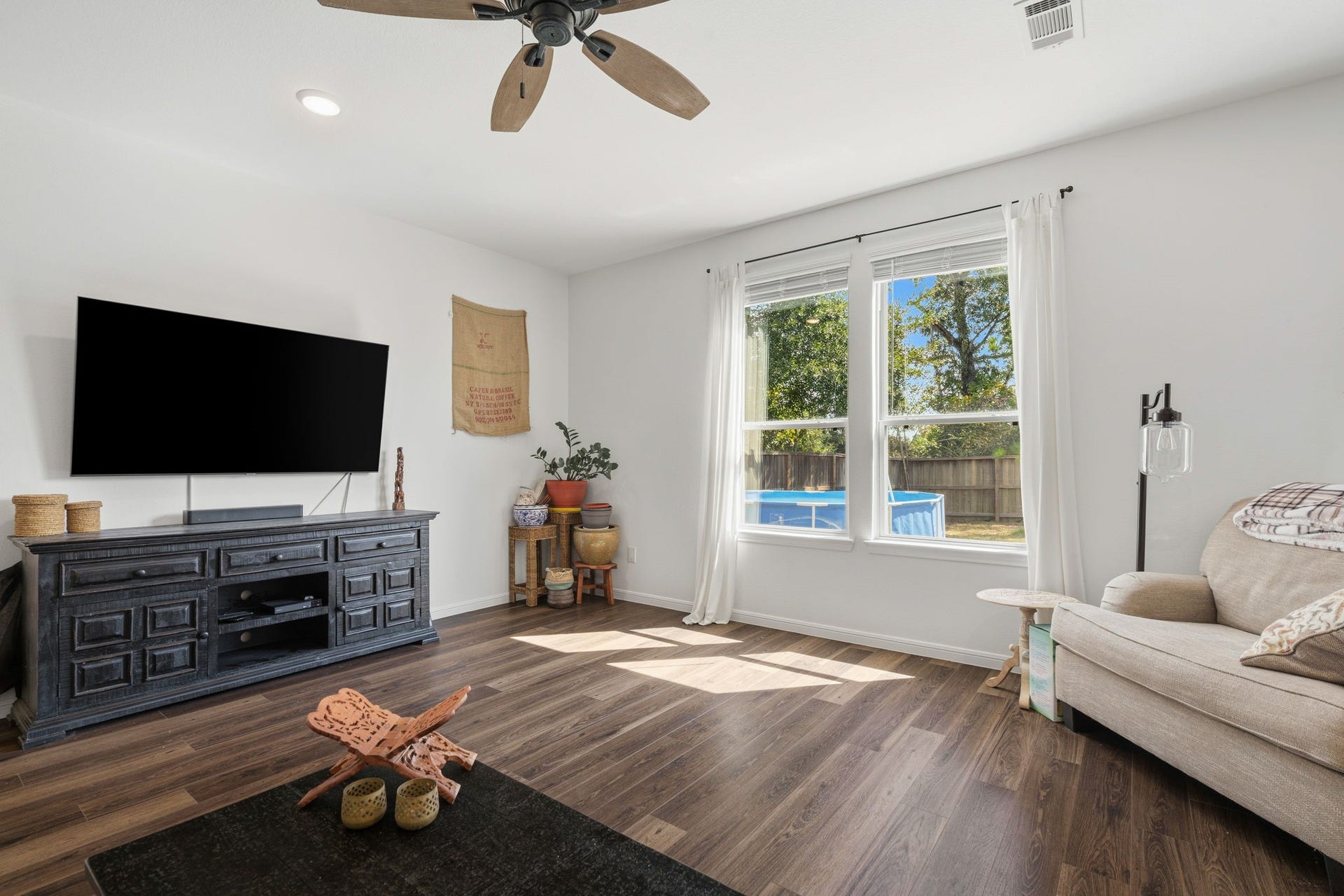 122 Ashwood Glade Lane, Conroe, TX 77378 Bright living room with large windows, modern ceiling fan, and stylish wood flooring, offering a cozy space for relaxation and entertainment.