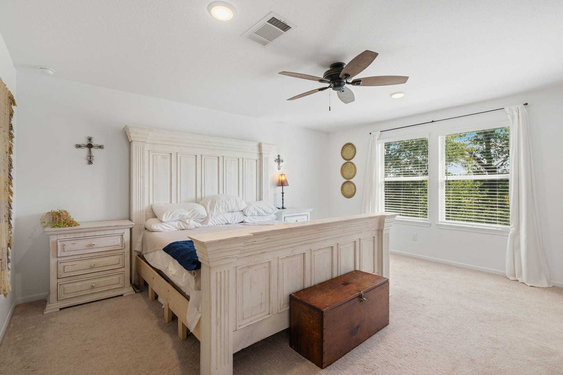 122 Ashwood Glade Lane, Conroe, TX 77378 Spacious bedroom with a cozy, rustic feel, featuring a large bed, elegant ceiling fan, and abundant natural light from two large windows.