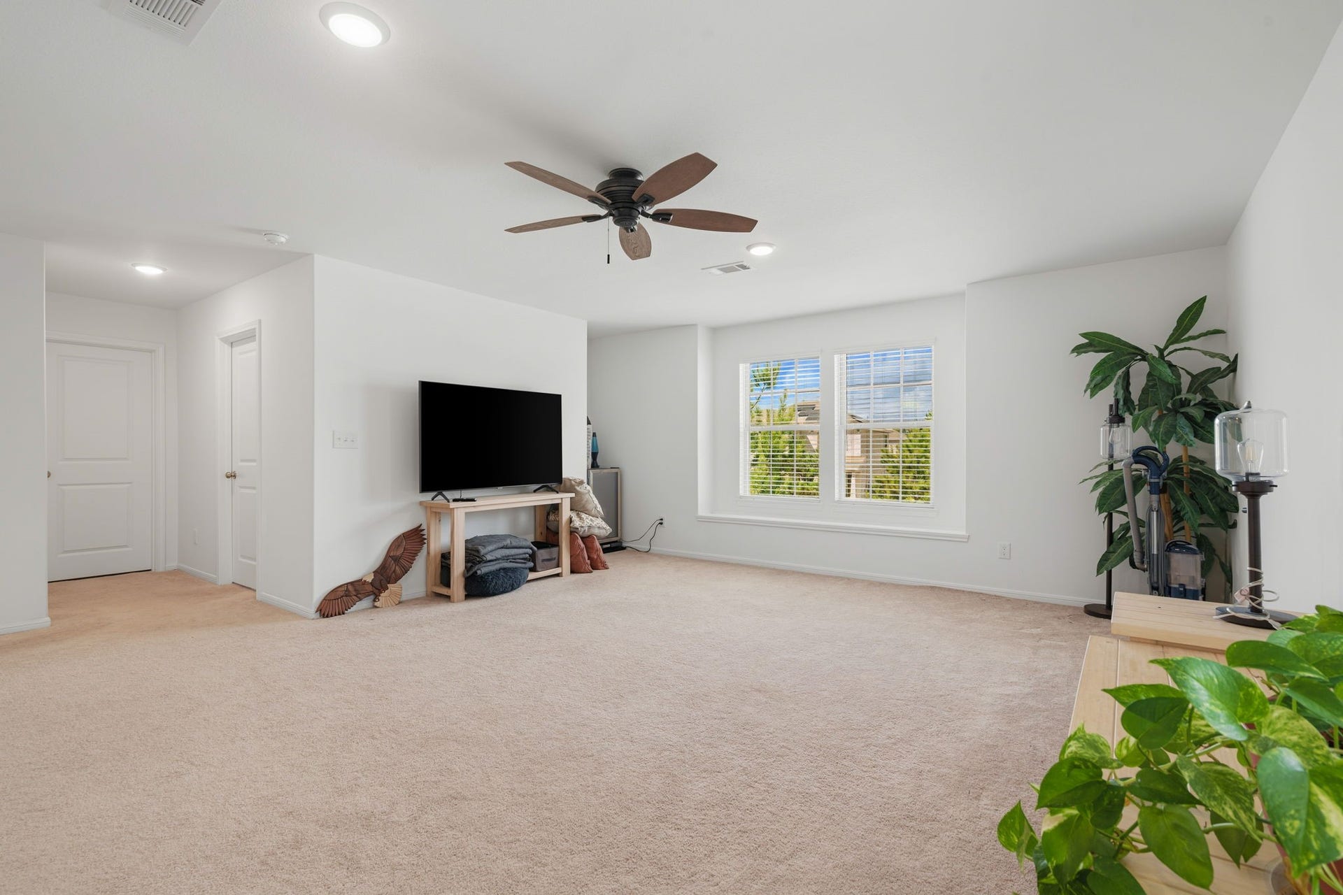 122 Ashwood Glade Lane, Conroe, TX 77378 Spacious living area with plush carpeting, ceiling fan, and a large window offering natural light. Ideal for relaxation and entertainment.