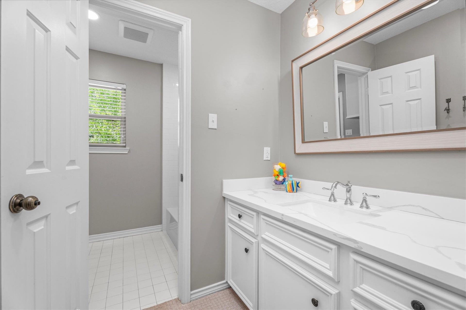 One of two secondary bathrooms is jack-and-jill style, with a private vanity area, updated with lighting, countertops, sink and fixtures in 2021.