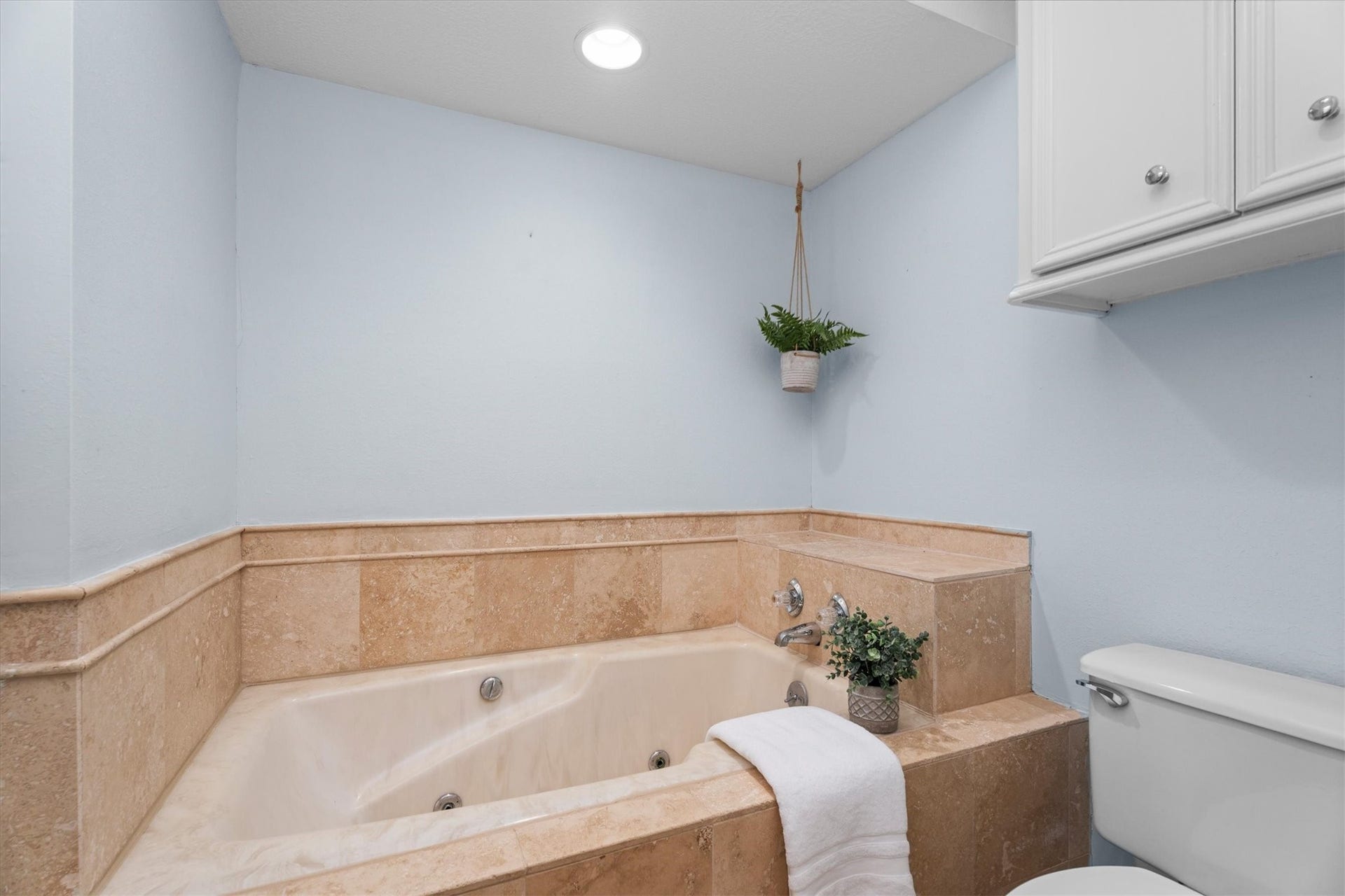 Around the corner from the vanity is a separate room with a shower, large tub, and additional overhead storage to the ceiling.